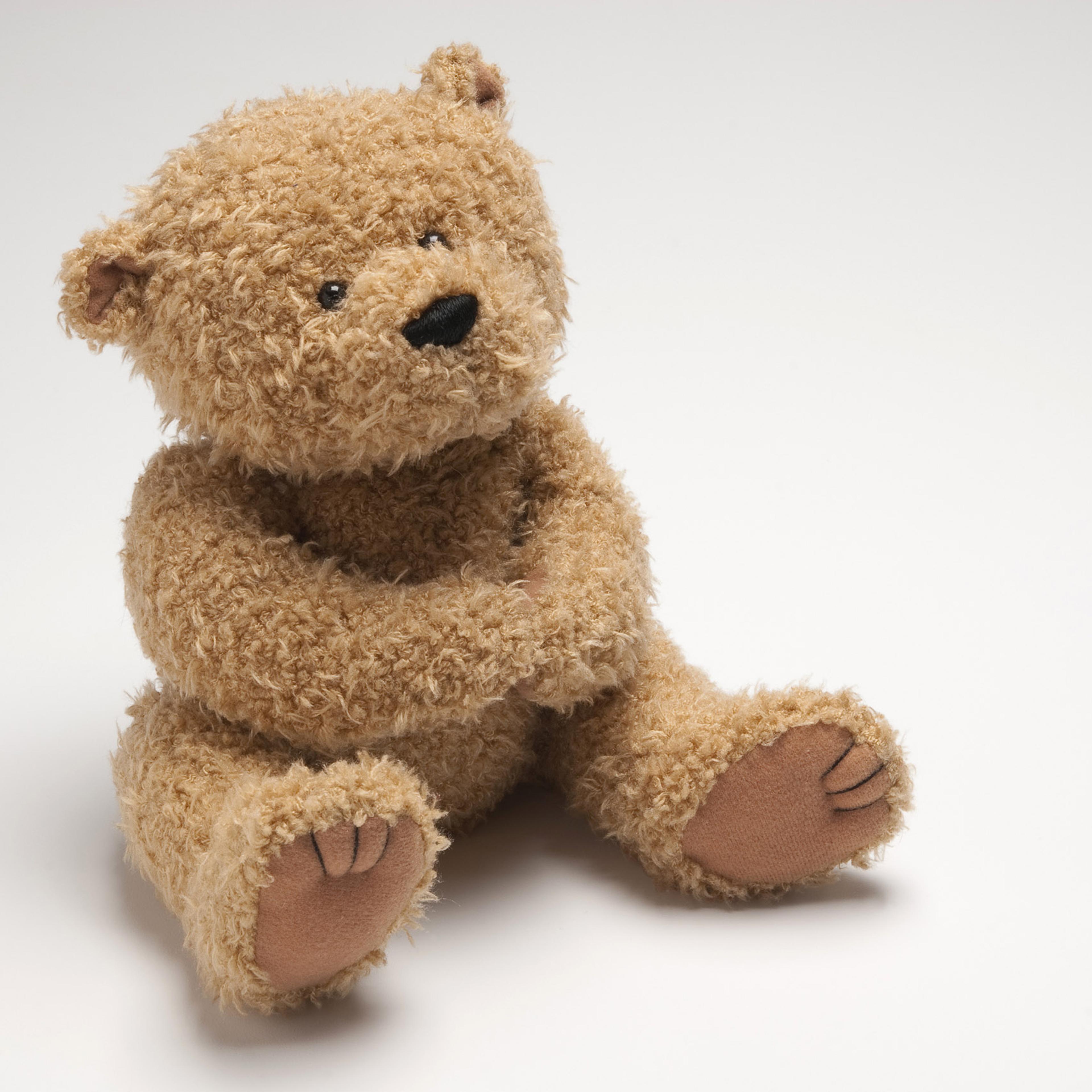 Light brown stuffed bear sitting on white surface