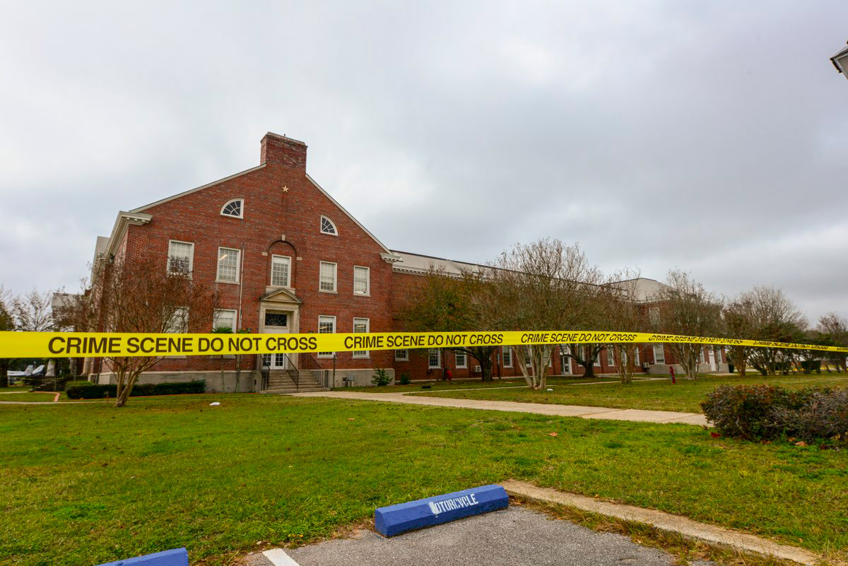Police tape stretches across a street near a building after an active shooting incident at a naval base in Pensacola