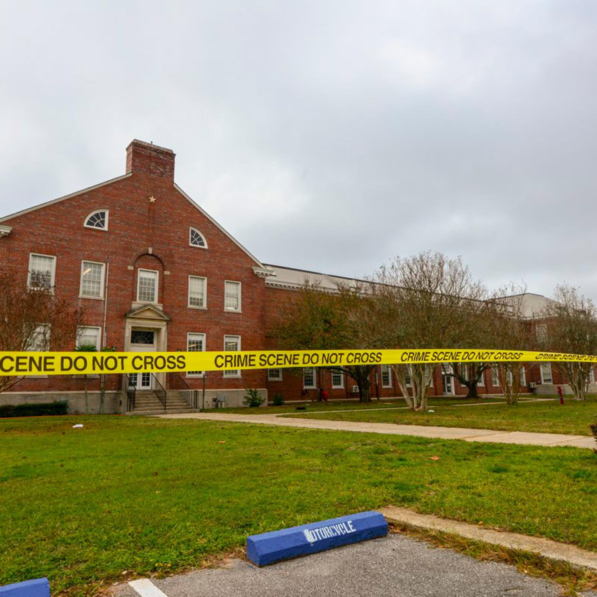 Police tape stretches across a street near a building after an active shooting incident at a naval base in Pensacola