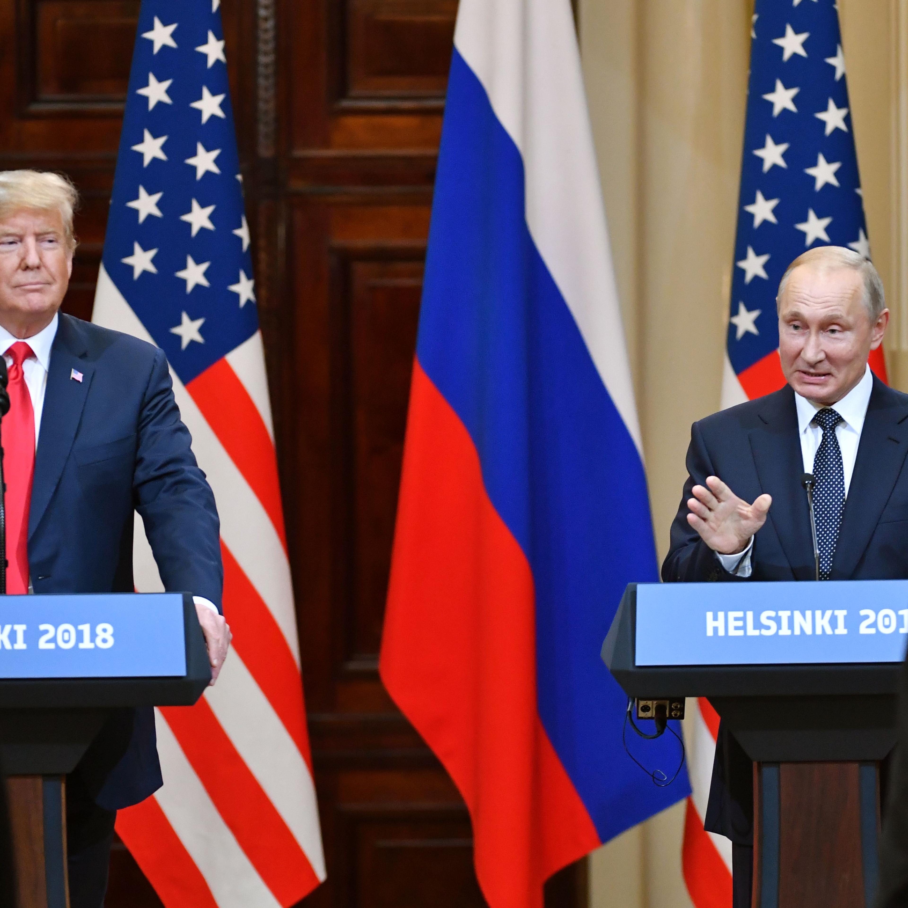 Presidents Trump and Putin stand in front of their nations' flags during a press conference
