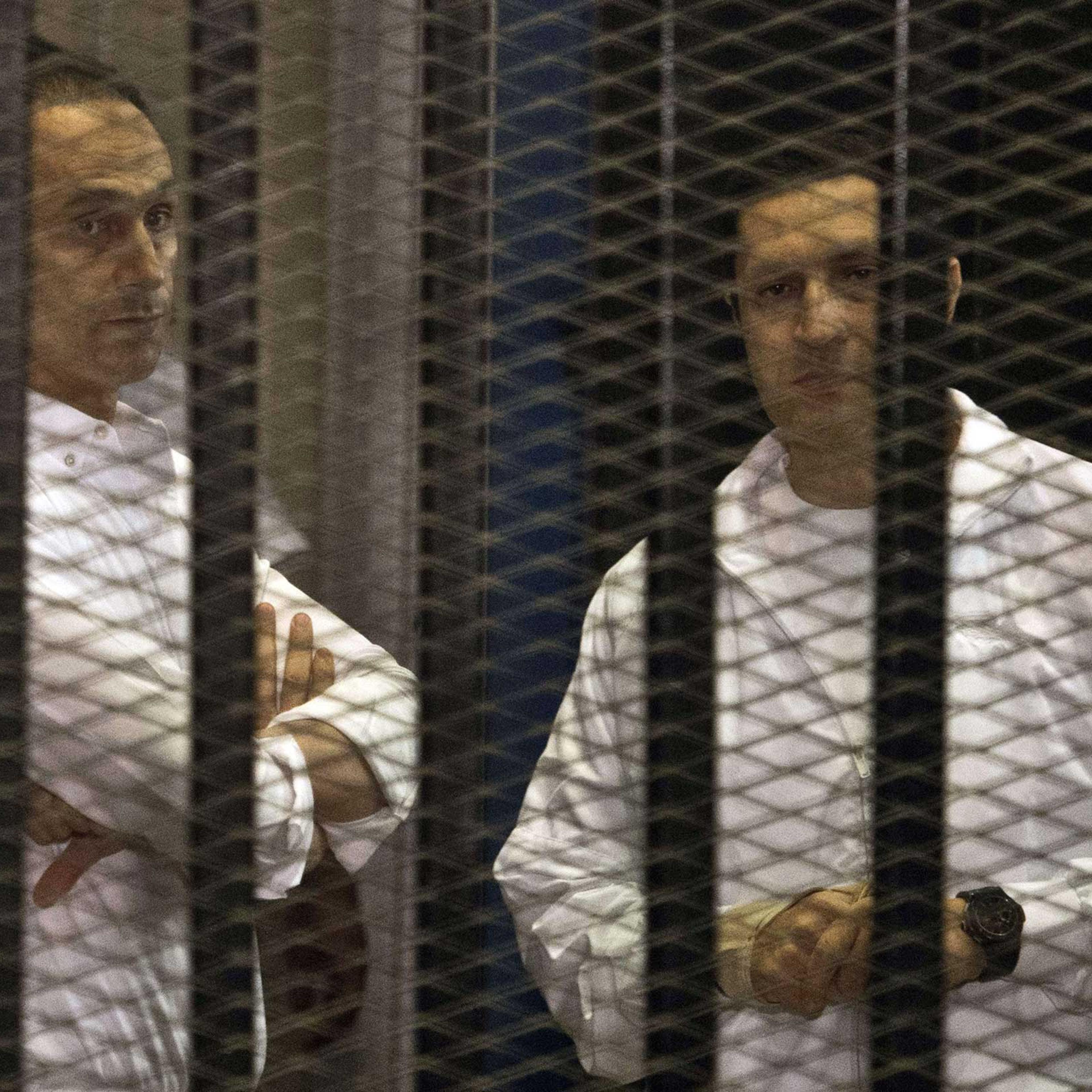 The sons of ousted Egyptian president Hosni Mubarak, Gamal and Alaa behind the defendants' cage during their retrial at the Police Academy in Cairo in 2013.