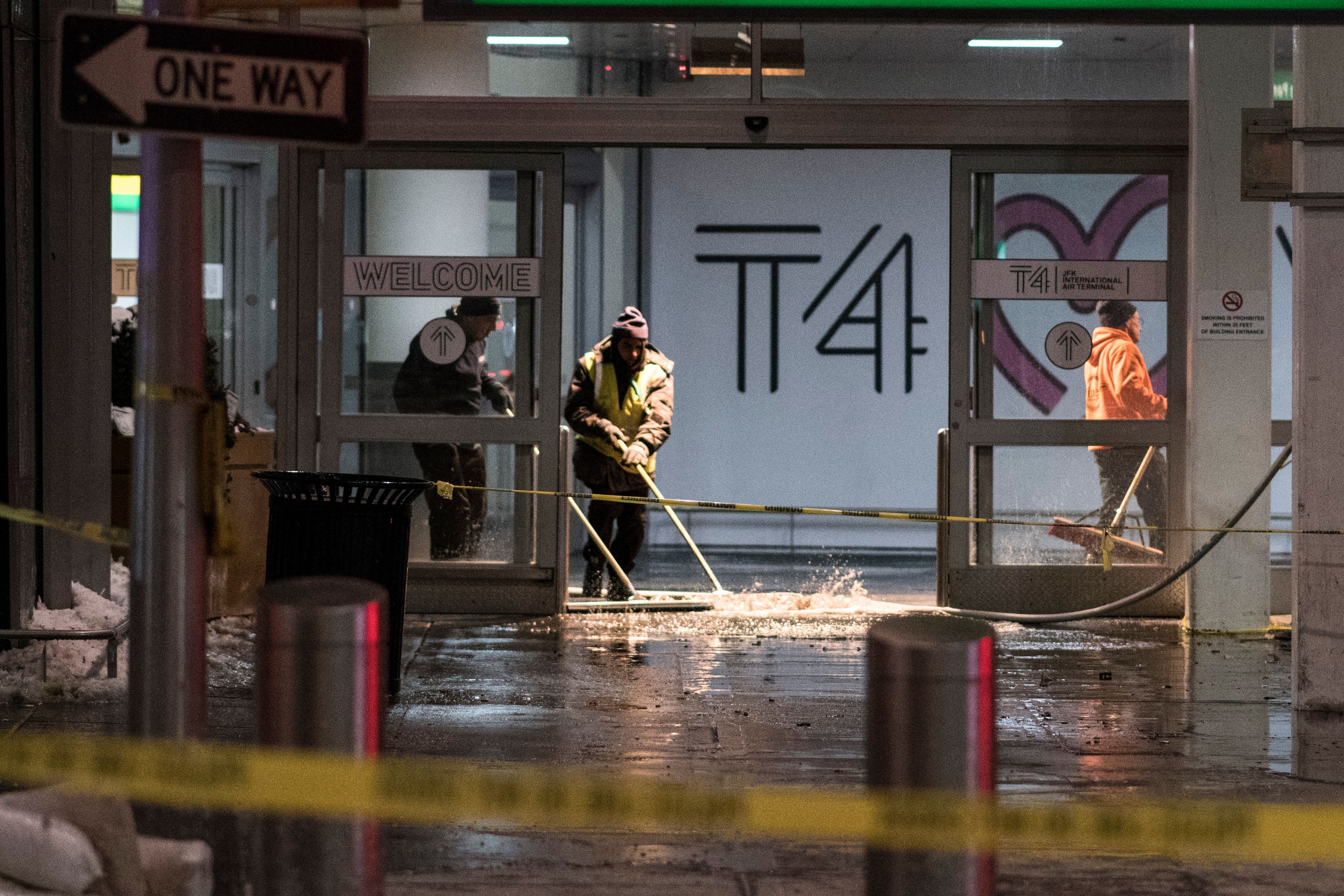 Workers sweep water from floor of the arrivals area at John F. Kennedy International airport's terminal 4, in New York on January 7, 2018.