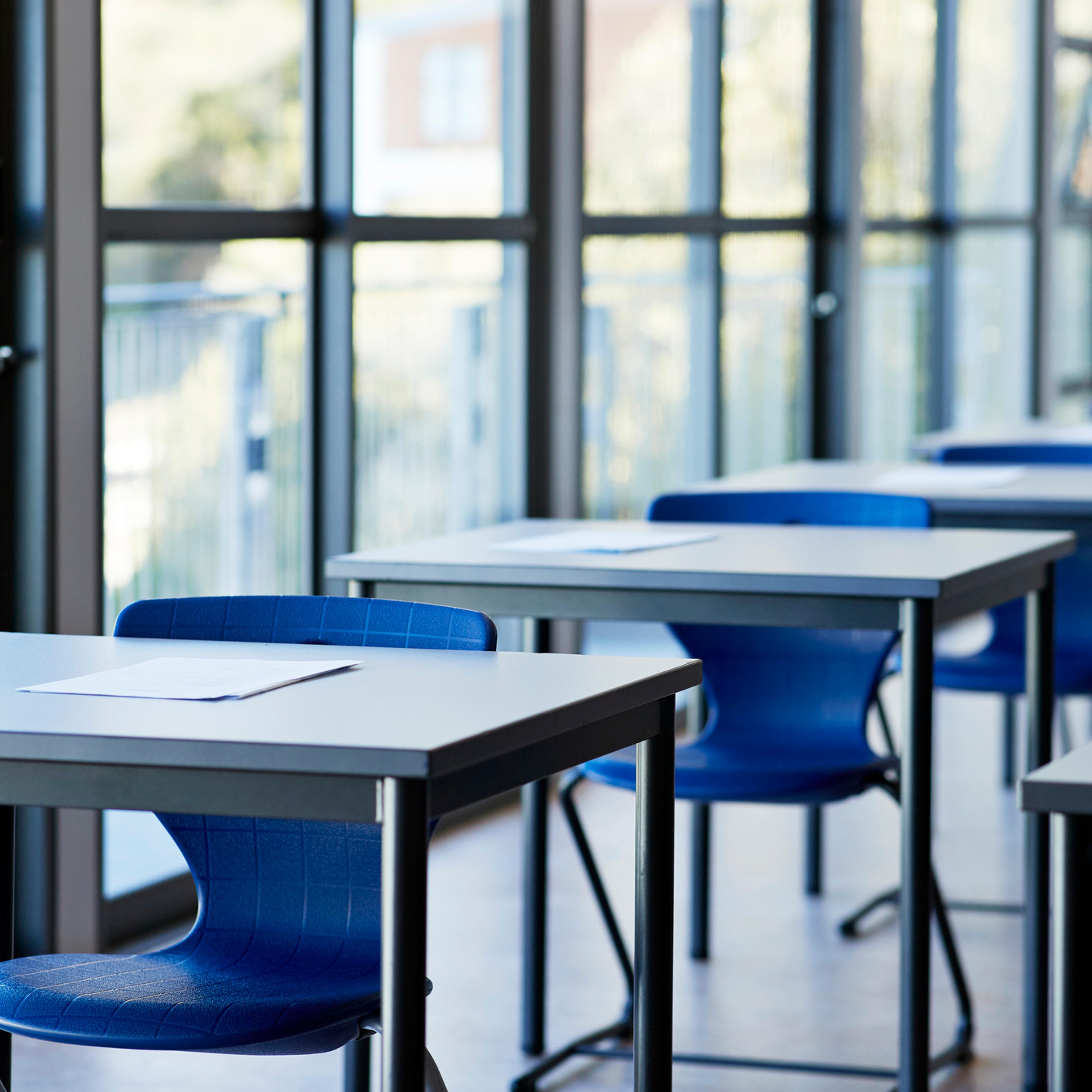 Papers on desks by window in classroom