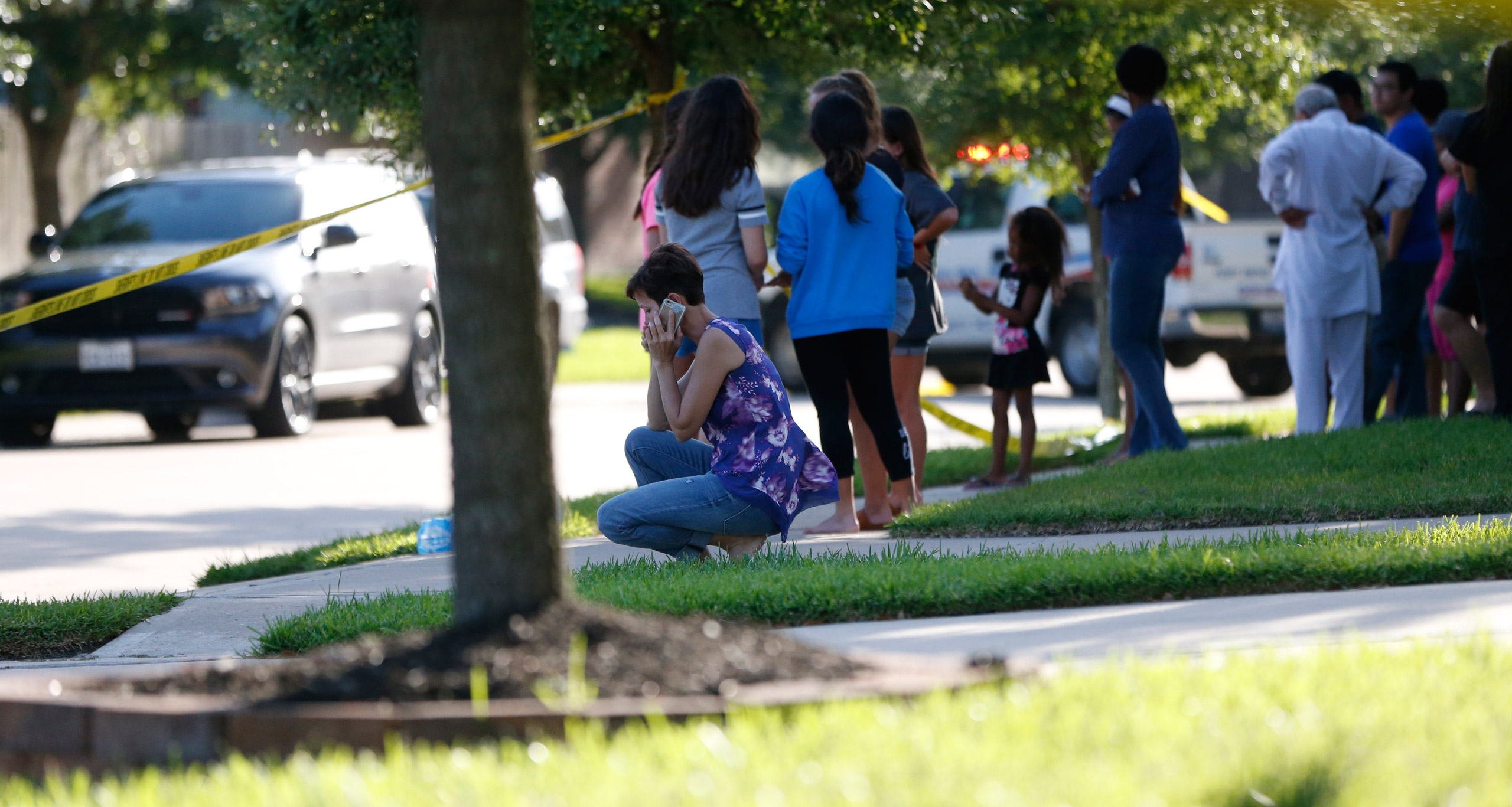In this Friday, June 24, 2016 photo, neighbors gather to watch as Fort Bend County Sheriffs department investigates a shooting at Blanchard Grove and Remson Hollow in Katy, Texas. Officials said a woman shot her two adult daughters - killing one of them 