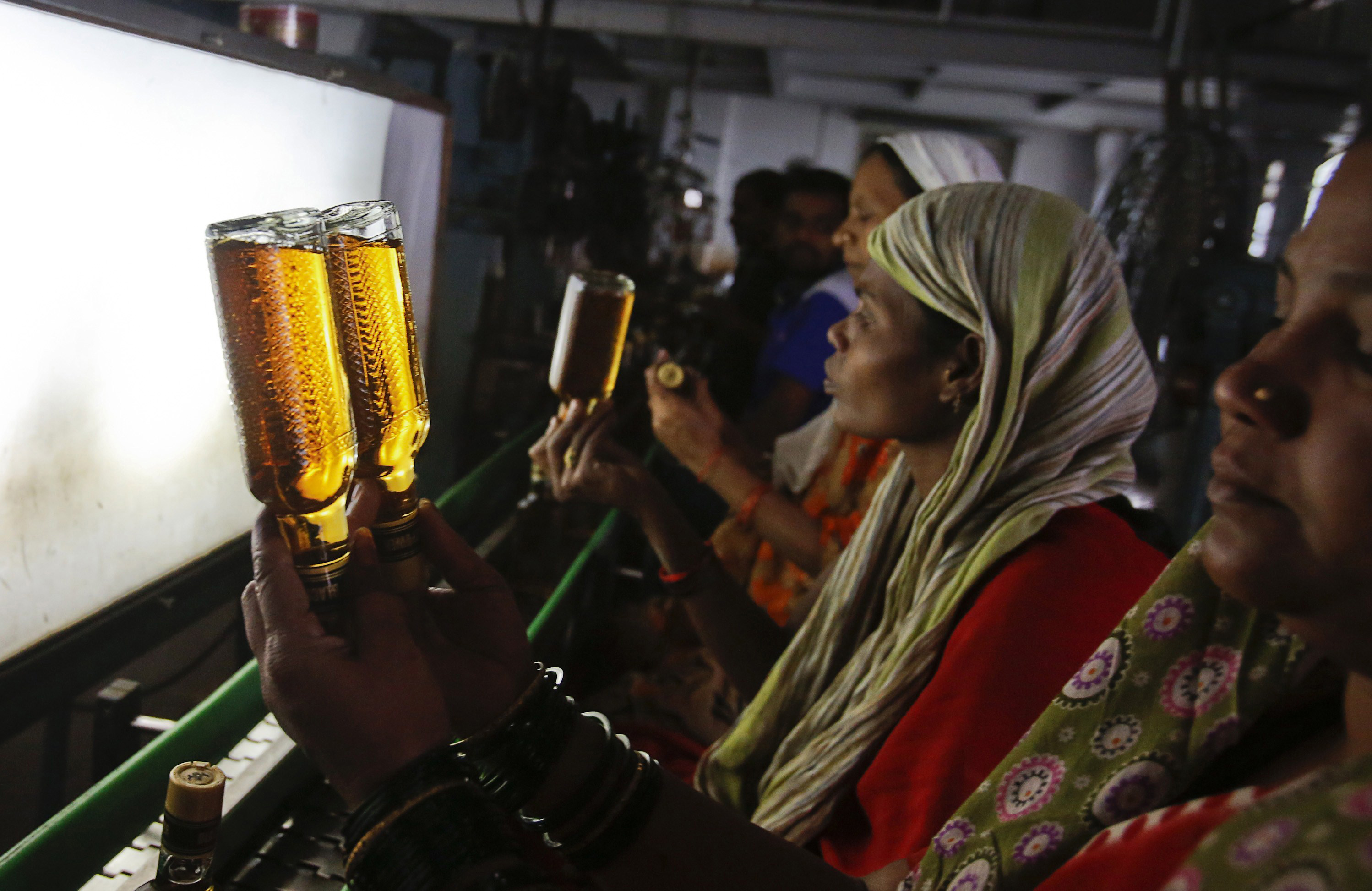 A bottling plant worker checks bottles of Black Power whisky for impurities at a Tilaknagar Industries distillery and bottling unit in Srirampur