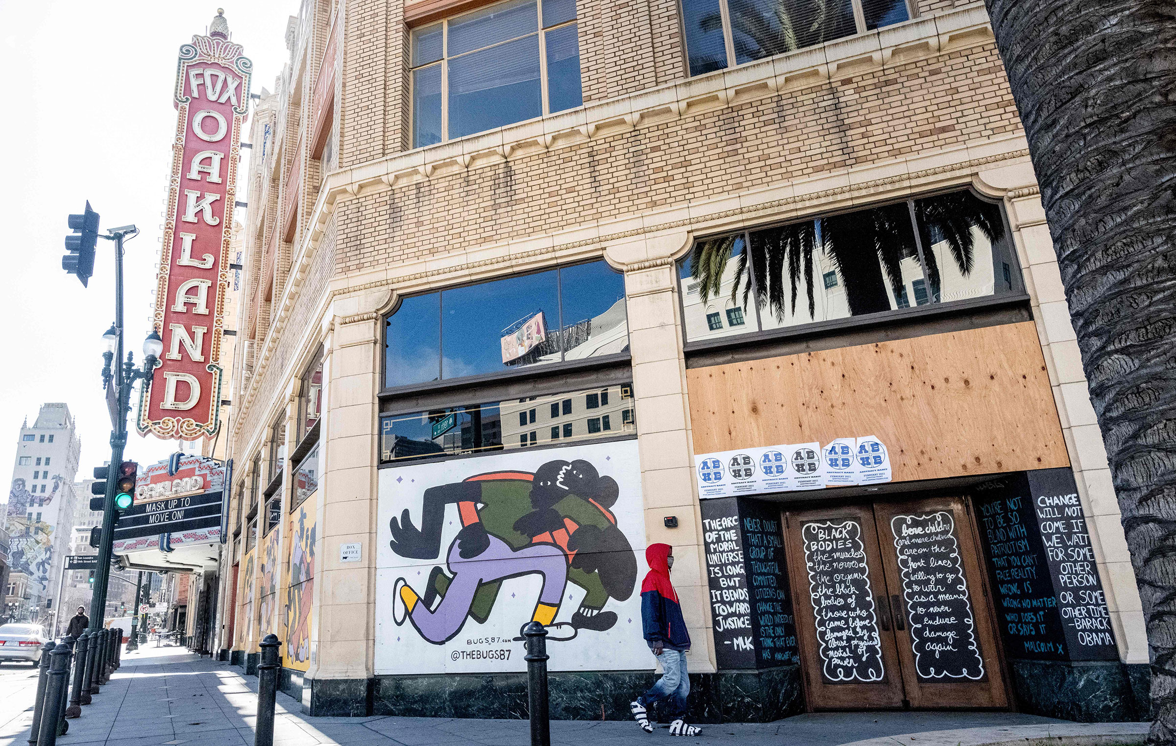 A person walks by a boarded-up shop in Oakland, California on February 12, 2021. - Racial minorities have borne the brunt of the Covid-19 pandemic in the United States, with higher rates of death, unemployment and business failure, and less success obtai