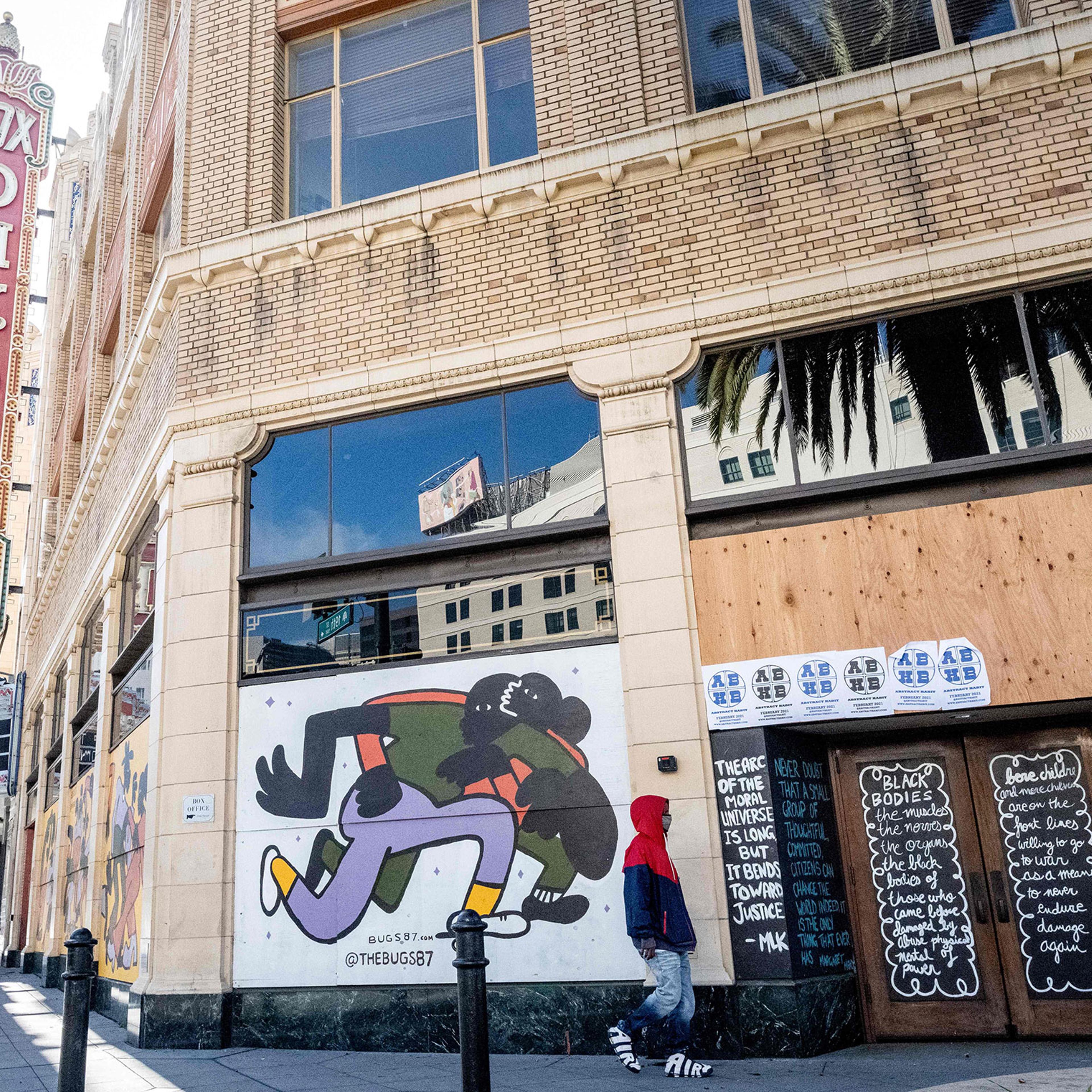 A person walks by a boarded-up shop in Oakland, California on February 12, 2021. - Racial minorities have borne the brunt of the Covid-19 pandemic in the United States, with higher rates of death, unemployment and business failure, and less success obtai