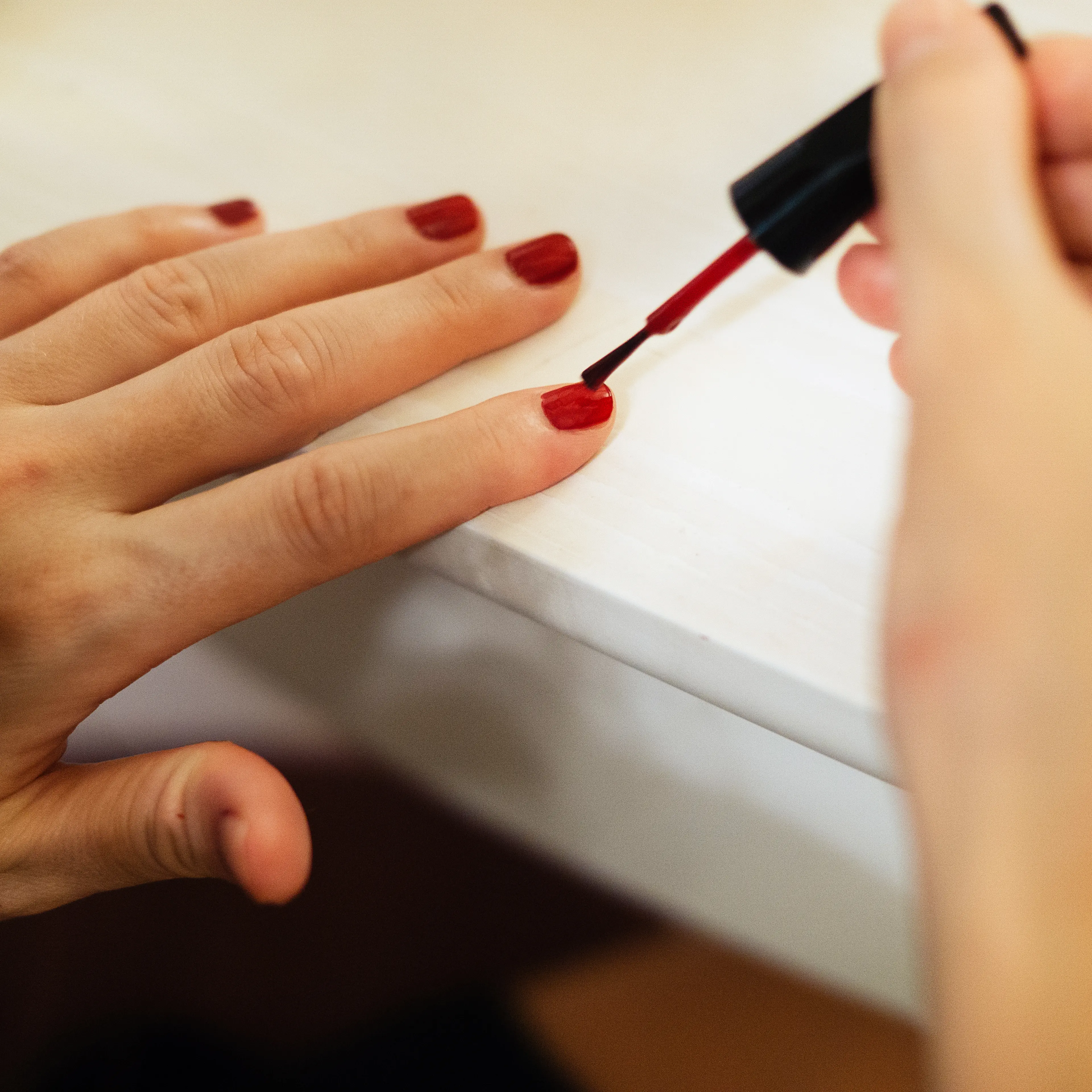 Young woman painting fingernails
