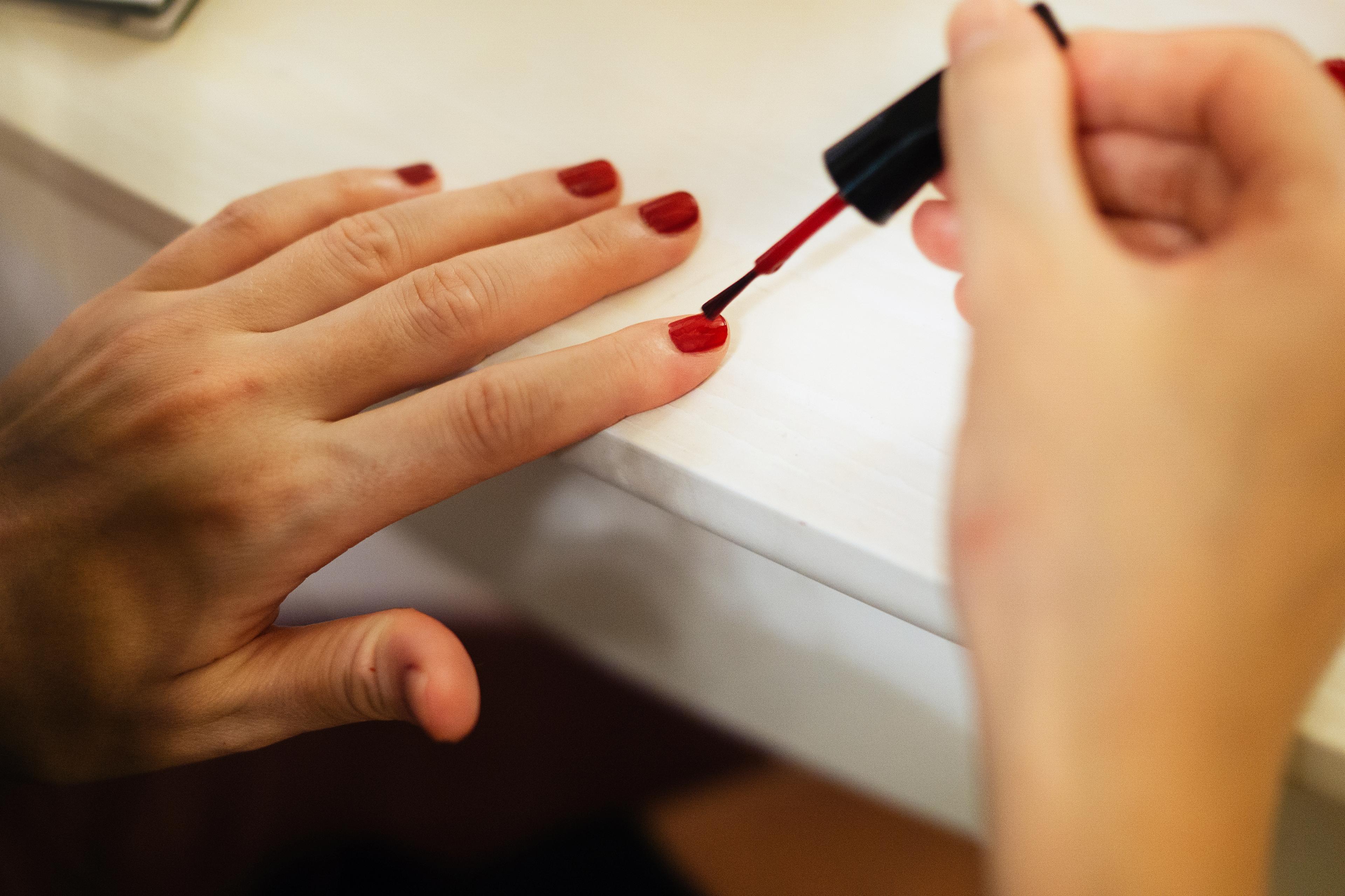Young woman painting fingernails
