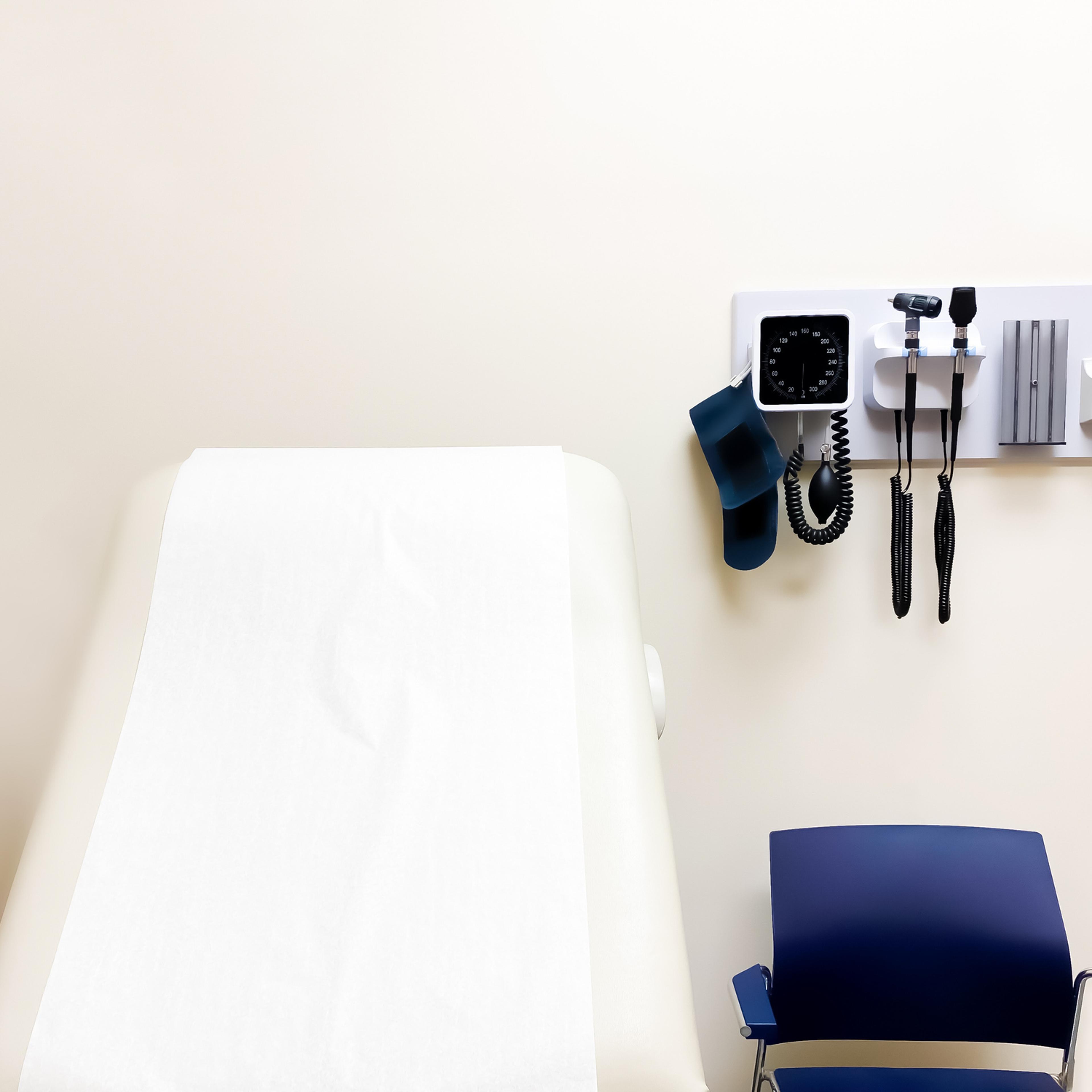 access to medical care: wall-mounted medical diagnostic equipment beside standard patient examination chair