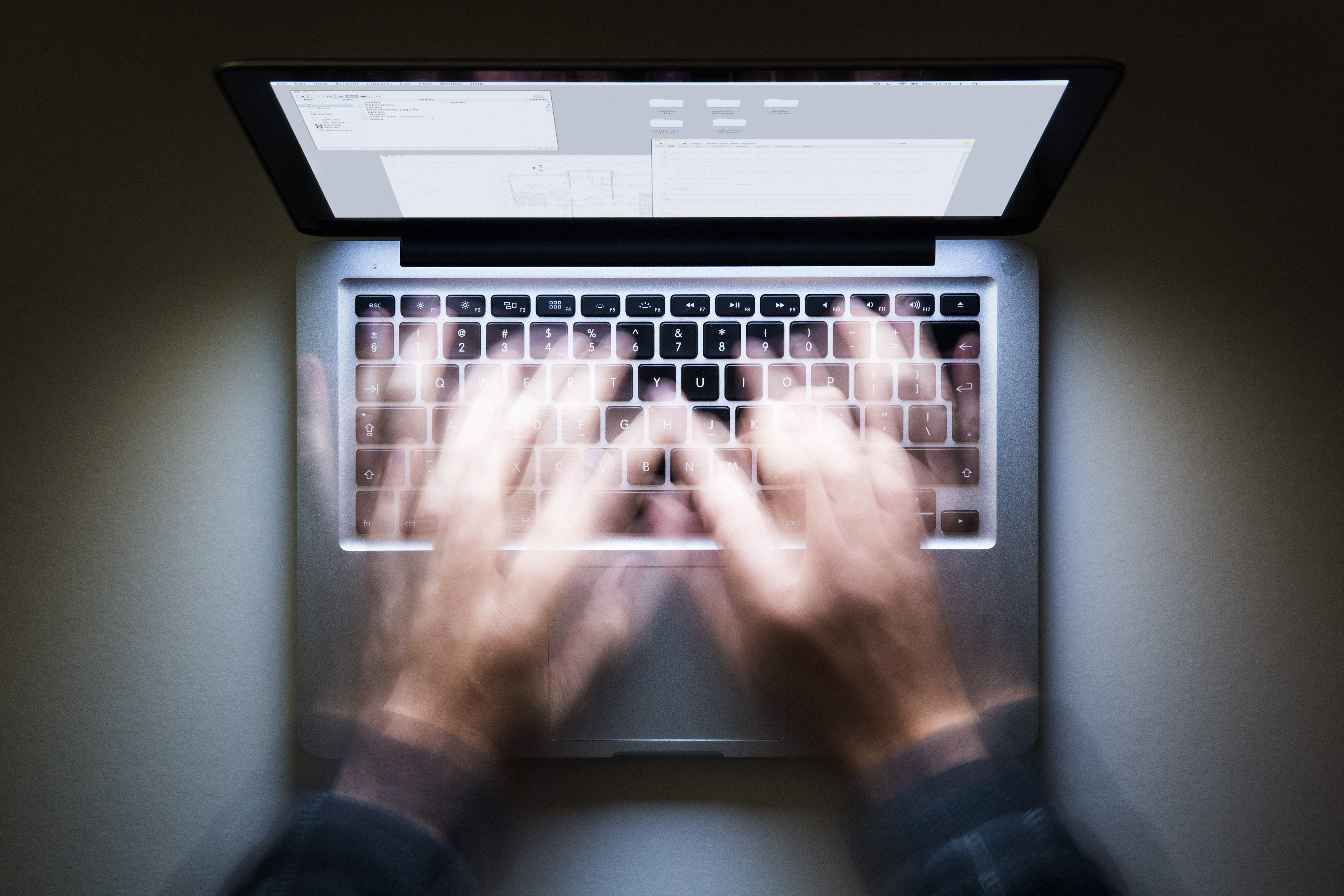 Laptop, speed typing, screen glowing in the dark