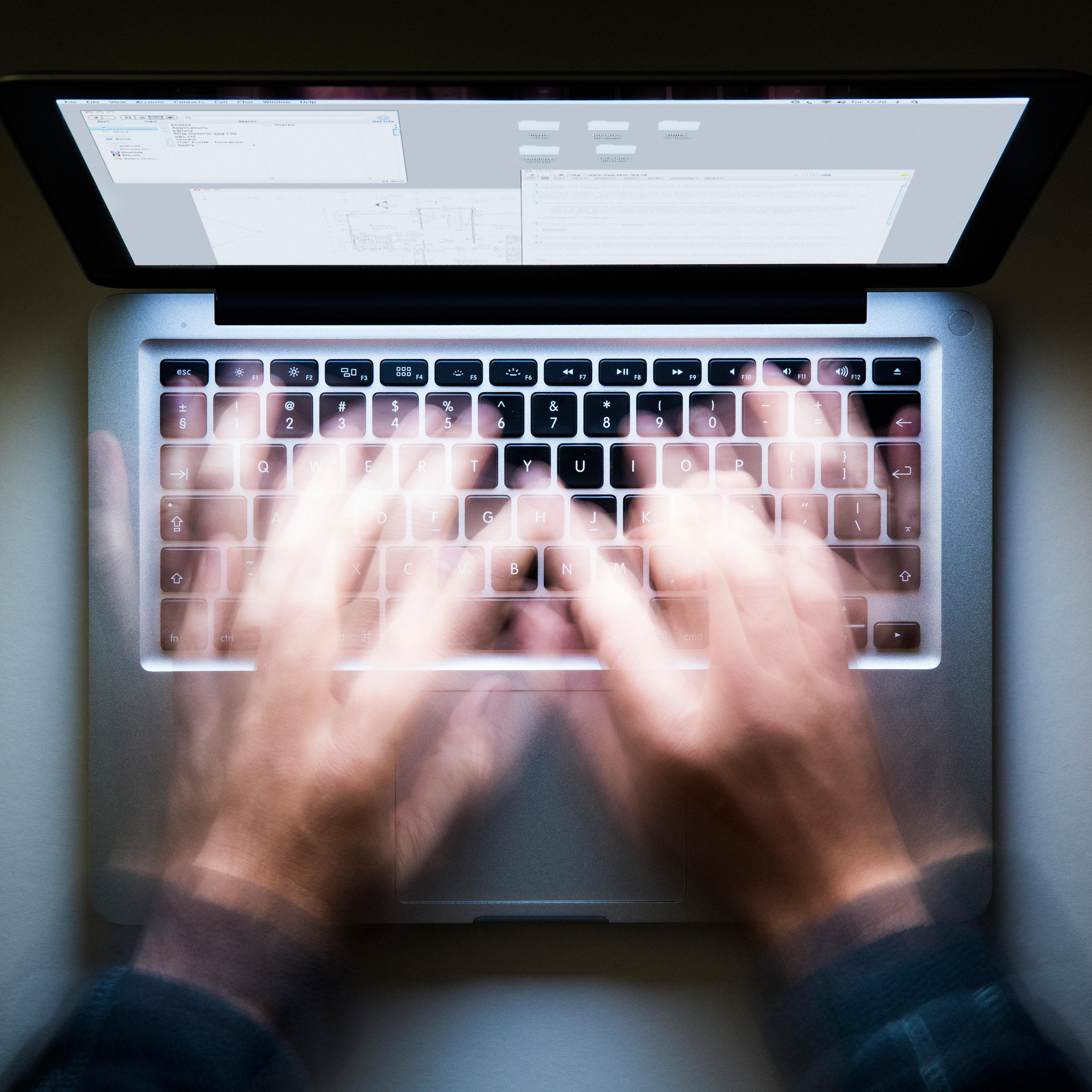 Laptop, speed typing, screen glowing in the dark