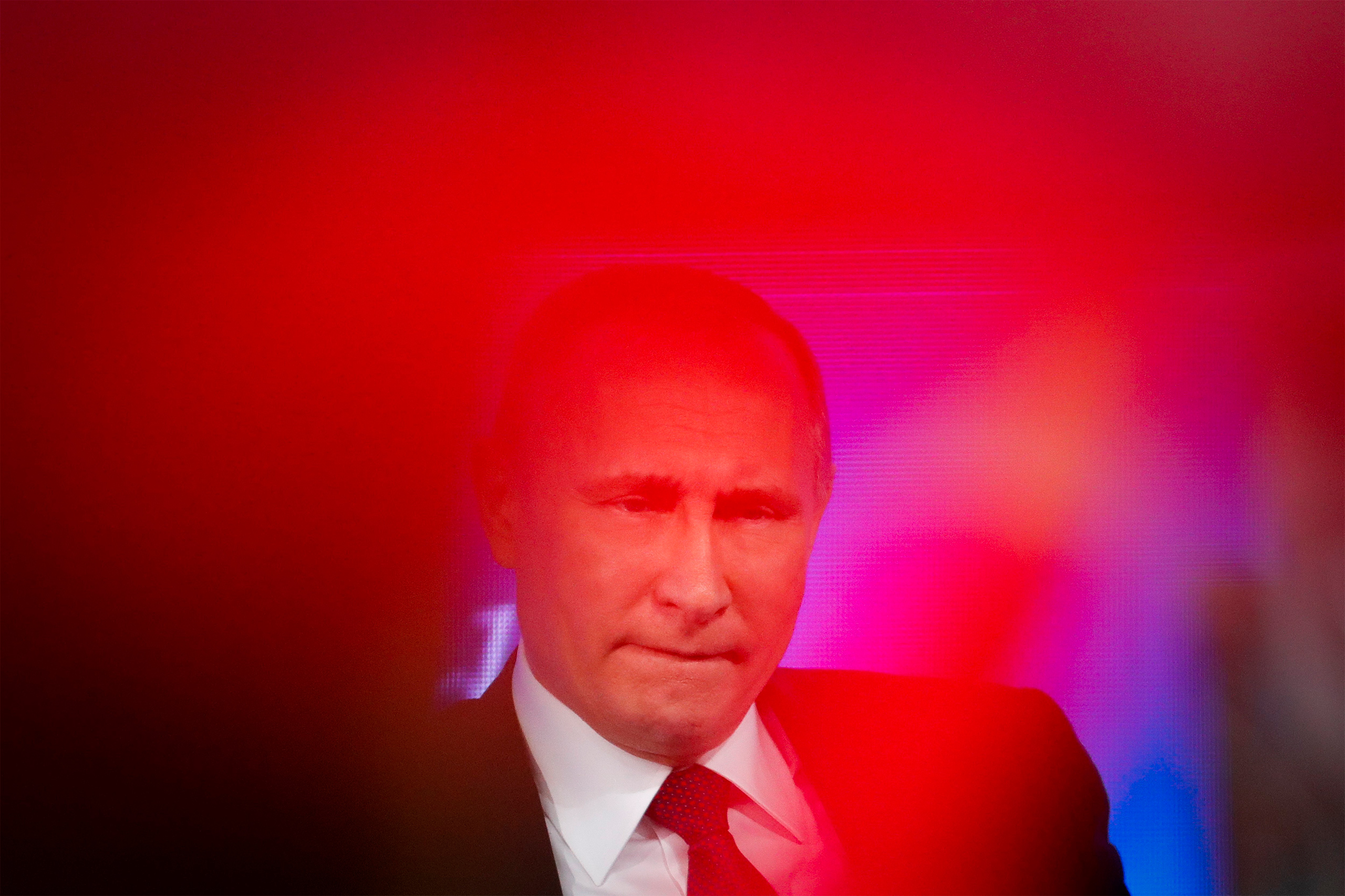 Russian President Vladimir Putin speaks as a journalist in red shows a poster with her question to him during his annual news conference in Moscow, Russia, Friday, Dec. 23, 2016. 
