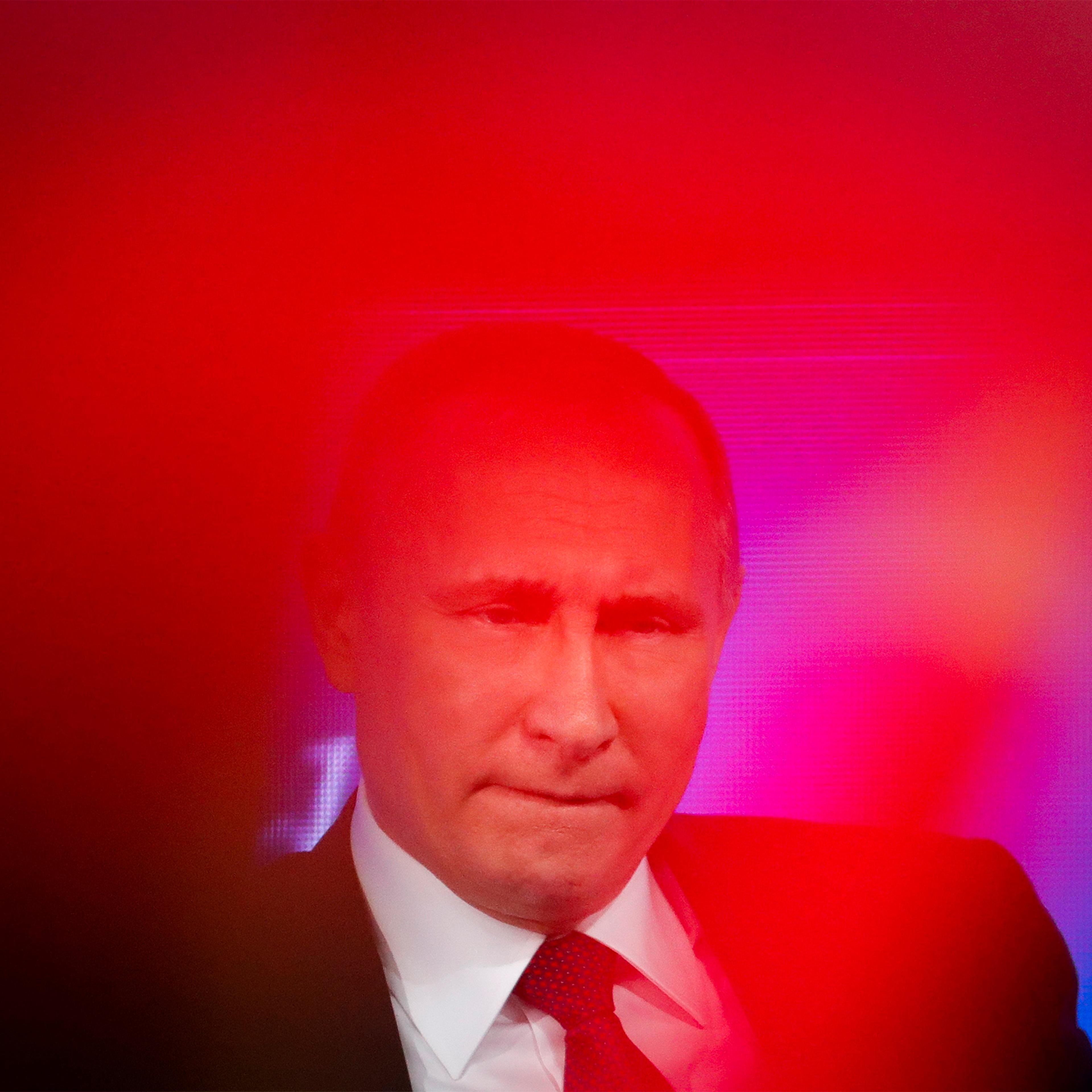 Russian President Vladimir Putin speaks as a journalist in red shows a poster with her question to him during his annual news conference in Moscow, Russia, Friday, Dec. 23, 2016.