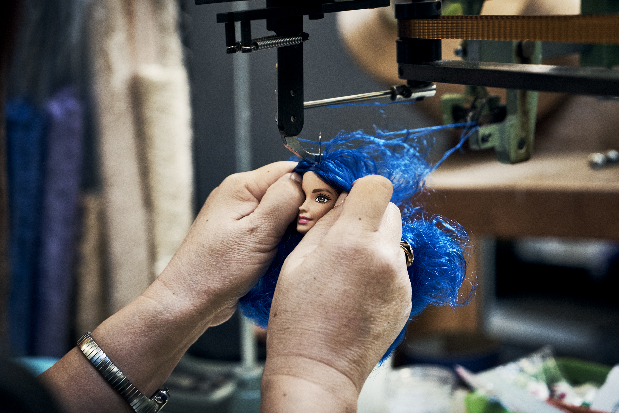A special machine attaches curvy Barbie's  hair. The process is called "rooting."