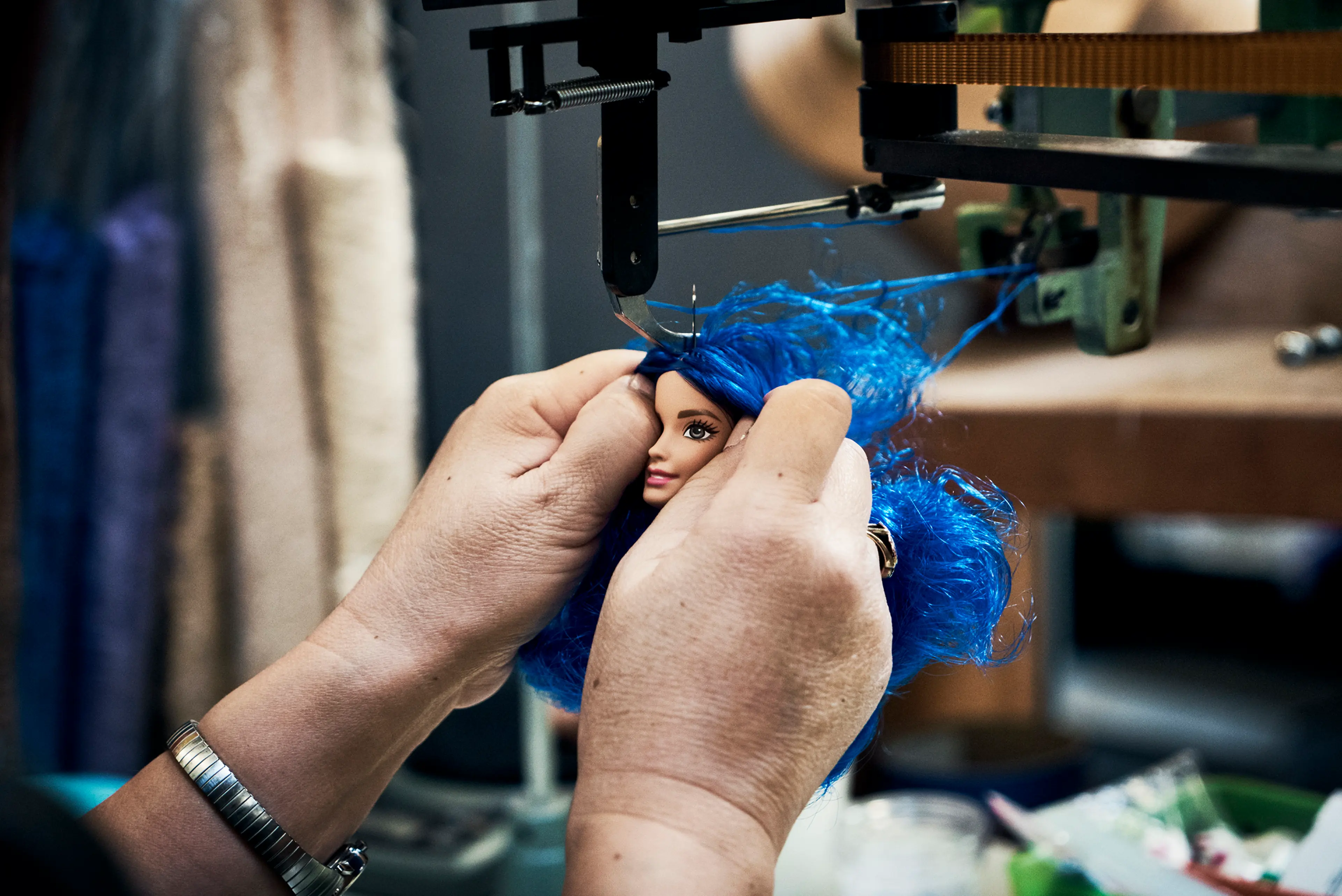 A special machine attaches curvy Barbie's hair. The process is called "rooting."
