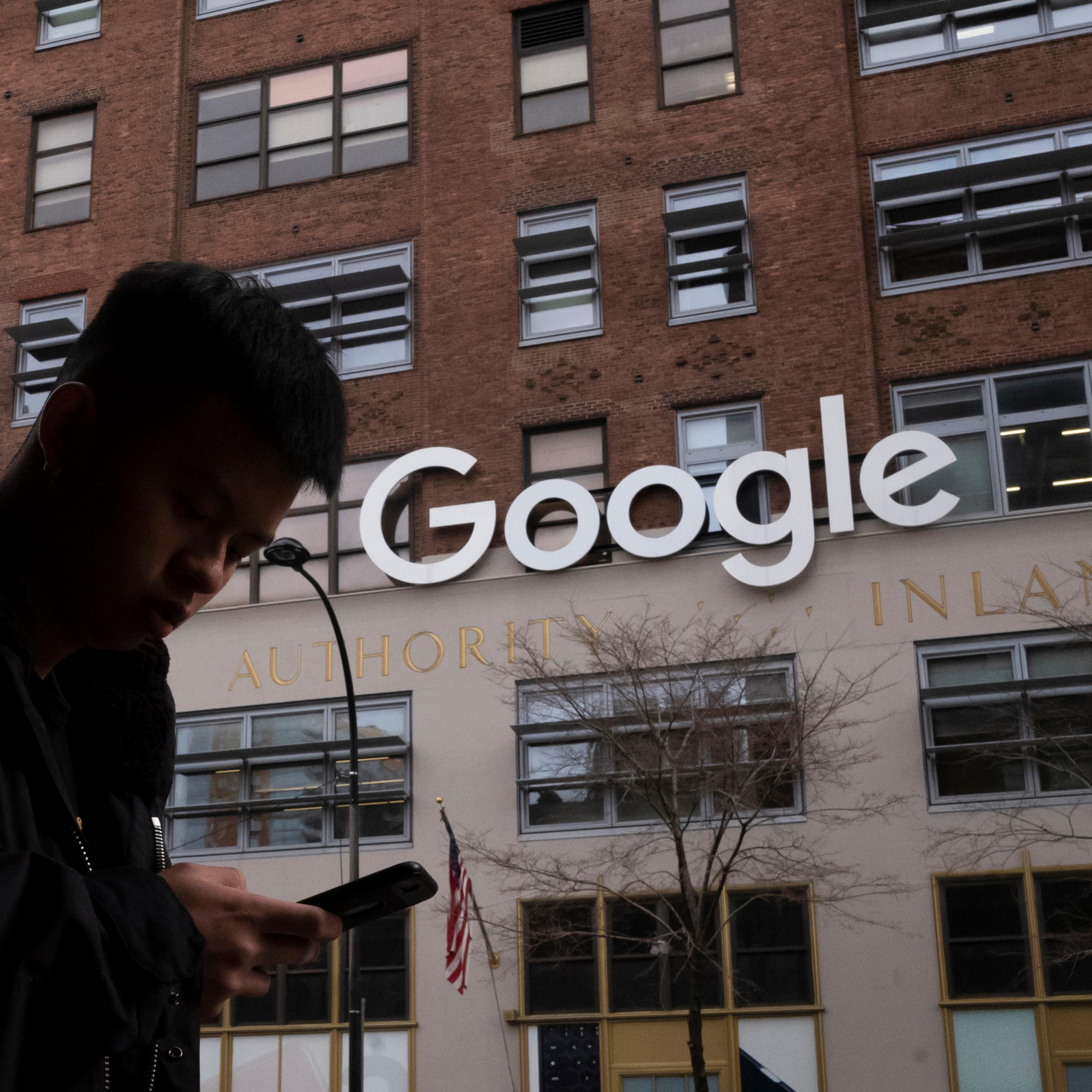 A man using a mobile phone walks past Google offices in New York