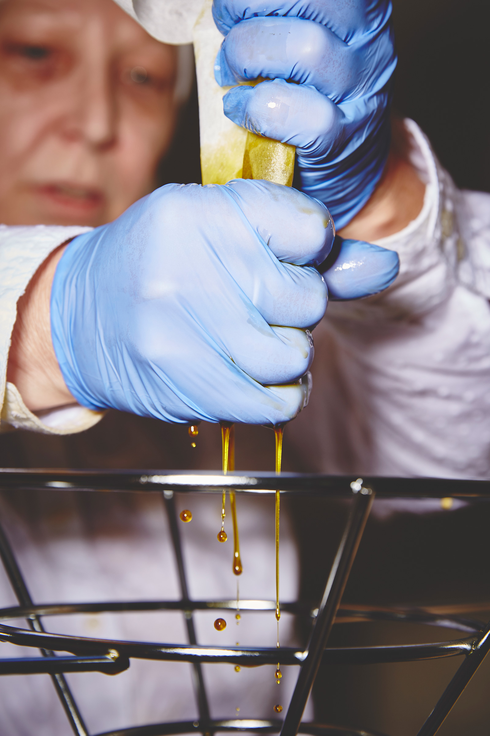 At a California facility, high-CBD cannabis extract is squeezed through a filter to produce a salve