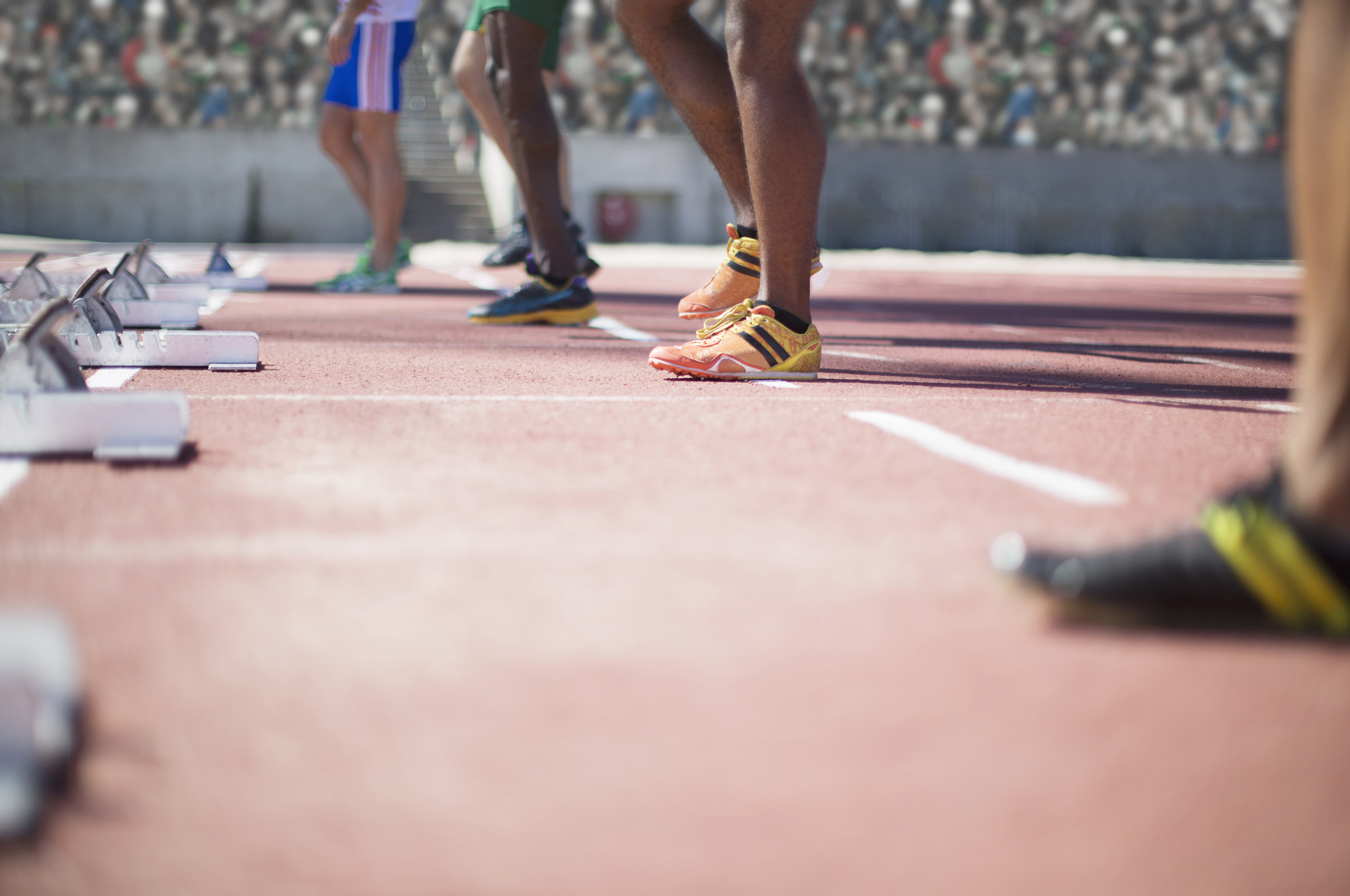 Runners standing at starting blocks on track