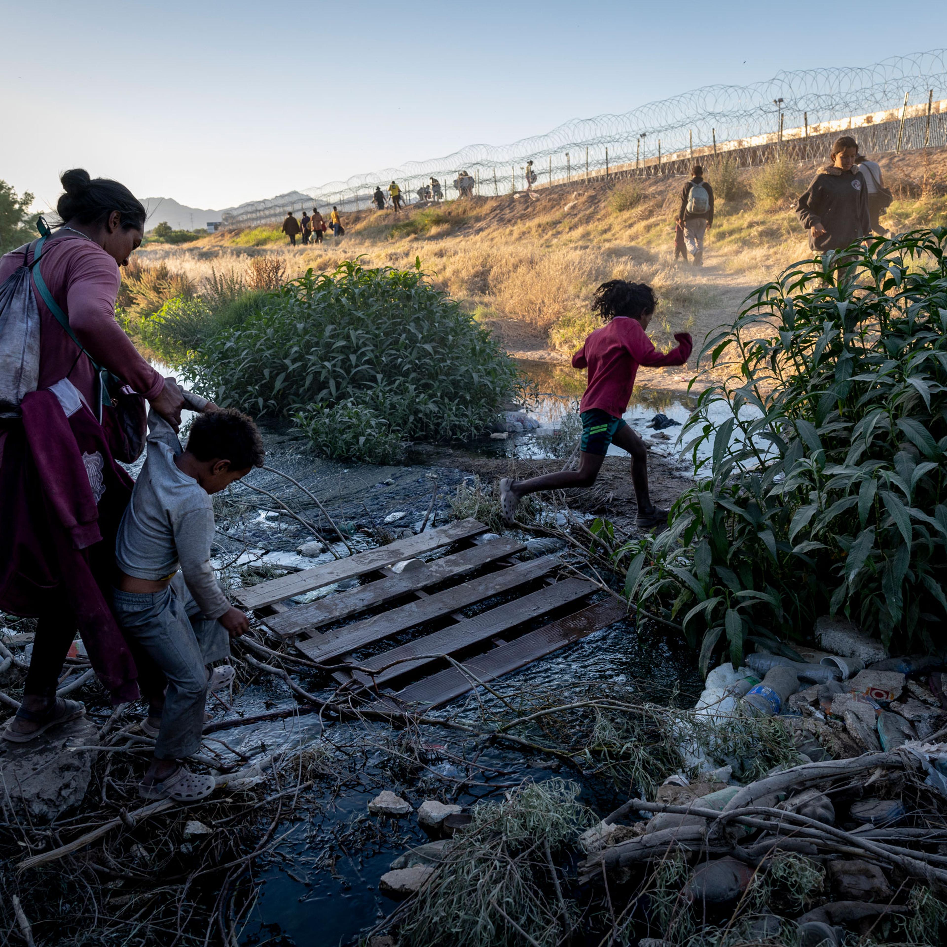 Immigrants step over a trickle of the Rio Grande while crossing the border from Mexico hoping to be processed for asylum in El Paso, Texas, on May 08, 2023.