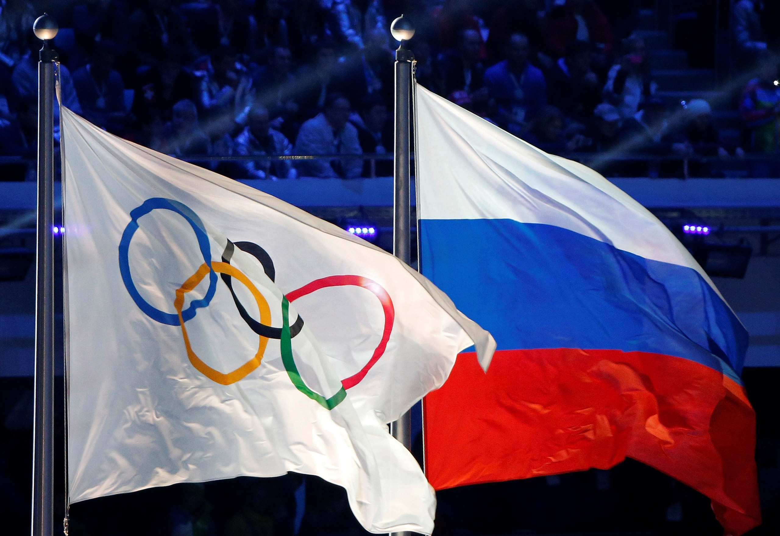 The Russian national flag (R) and the Olympic flag are seen during the closing ceremony for the 2014 Sochi Winter Olympics, Russia, February 23, 2014. REUTERS/Jim Young/File Photo - RTX2E5JG