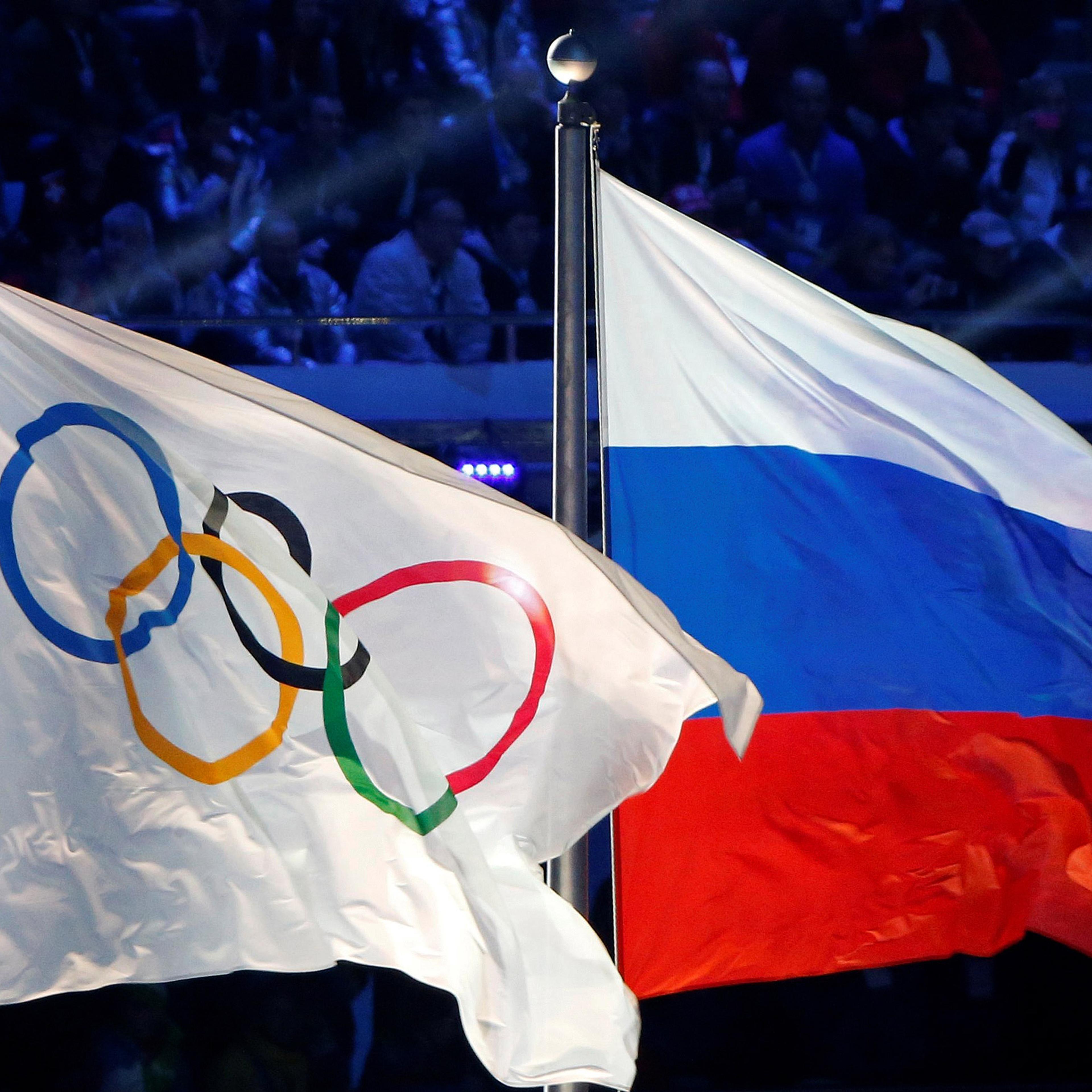 The Russian national flag (R) and the Olympic flag are seen during the closing ceremony for the 2014 Sochi Winter Olympics, Russia, February 23, 2014. REUTERS/Jim Young/File Photo - RTX2E5JG