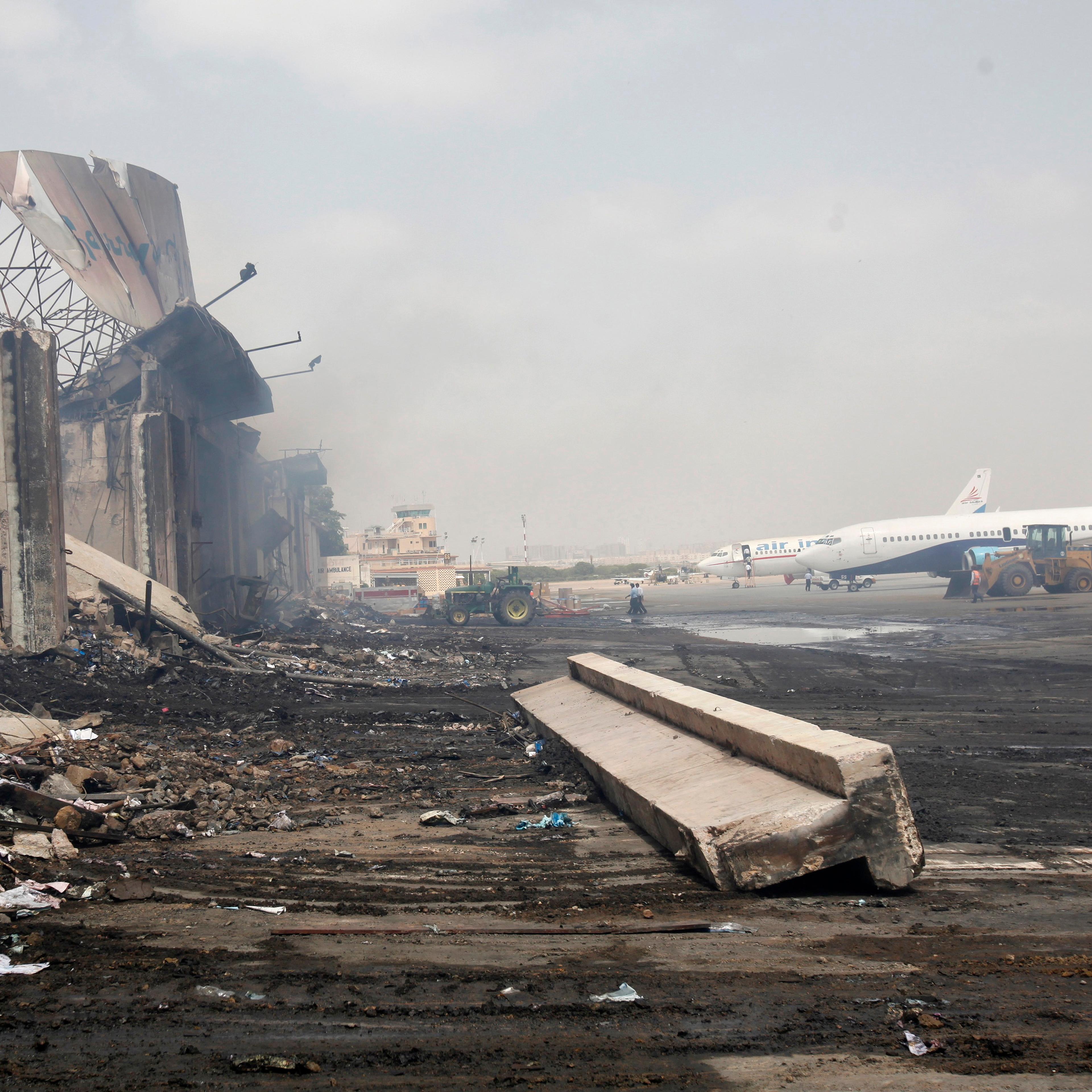 Planes are seen near a section of a damaged building at Jinnah International Airport, after Sunday's attack by Taliban militants, in Karachi
