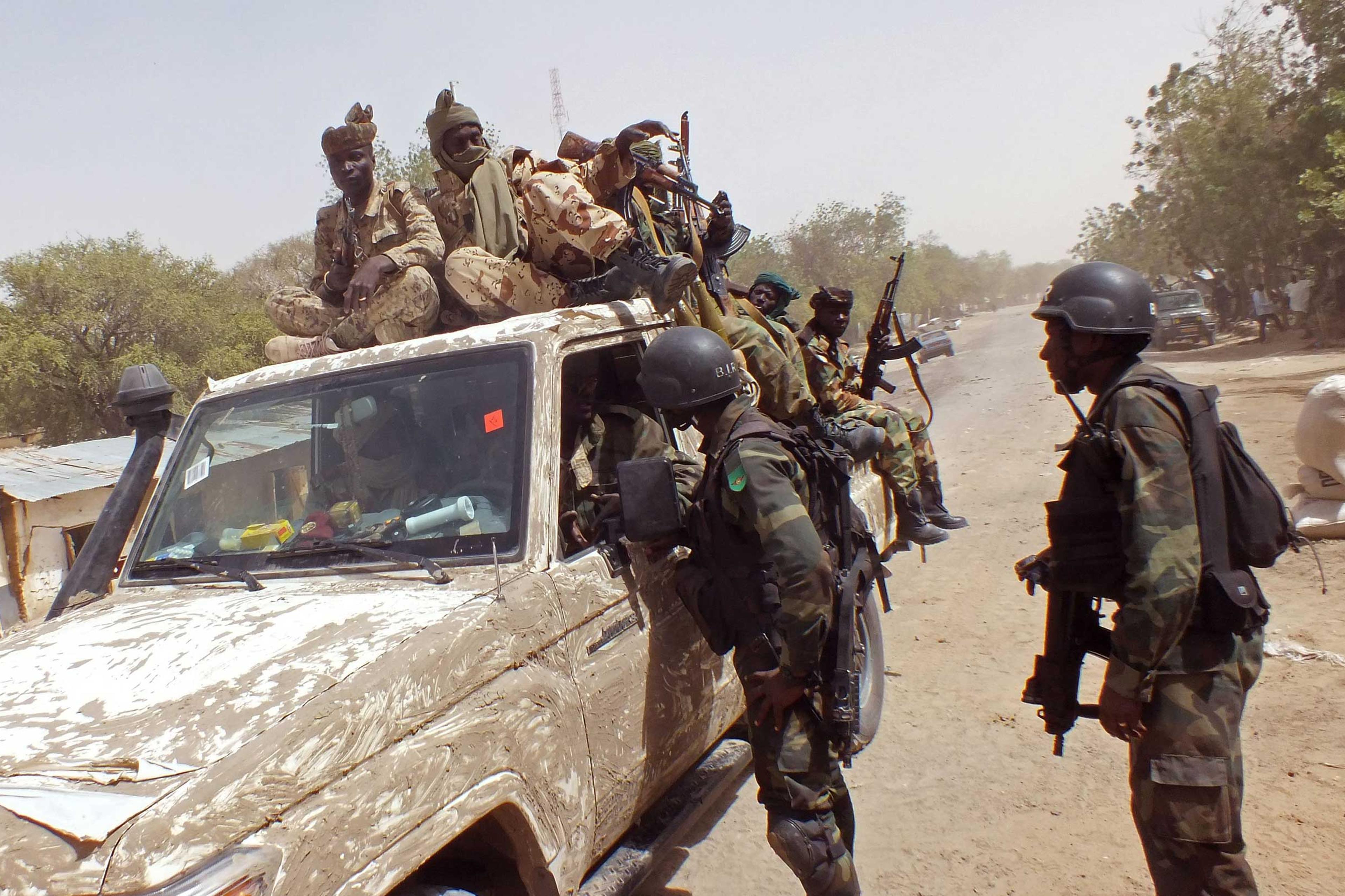 Chadian soldiers on top of a truck, left, speak to Cameroon soldiers, right, standing next to the truck, on the border between Cameroon and Nigeria as they form part of the force to combat regional Islamic extremists force's including Boko Haram, near th