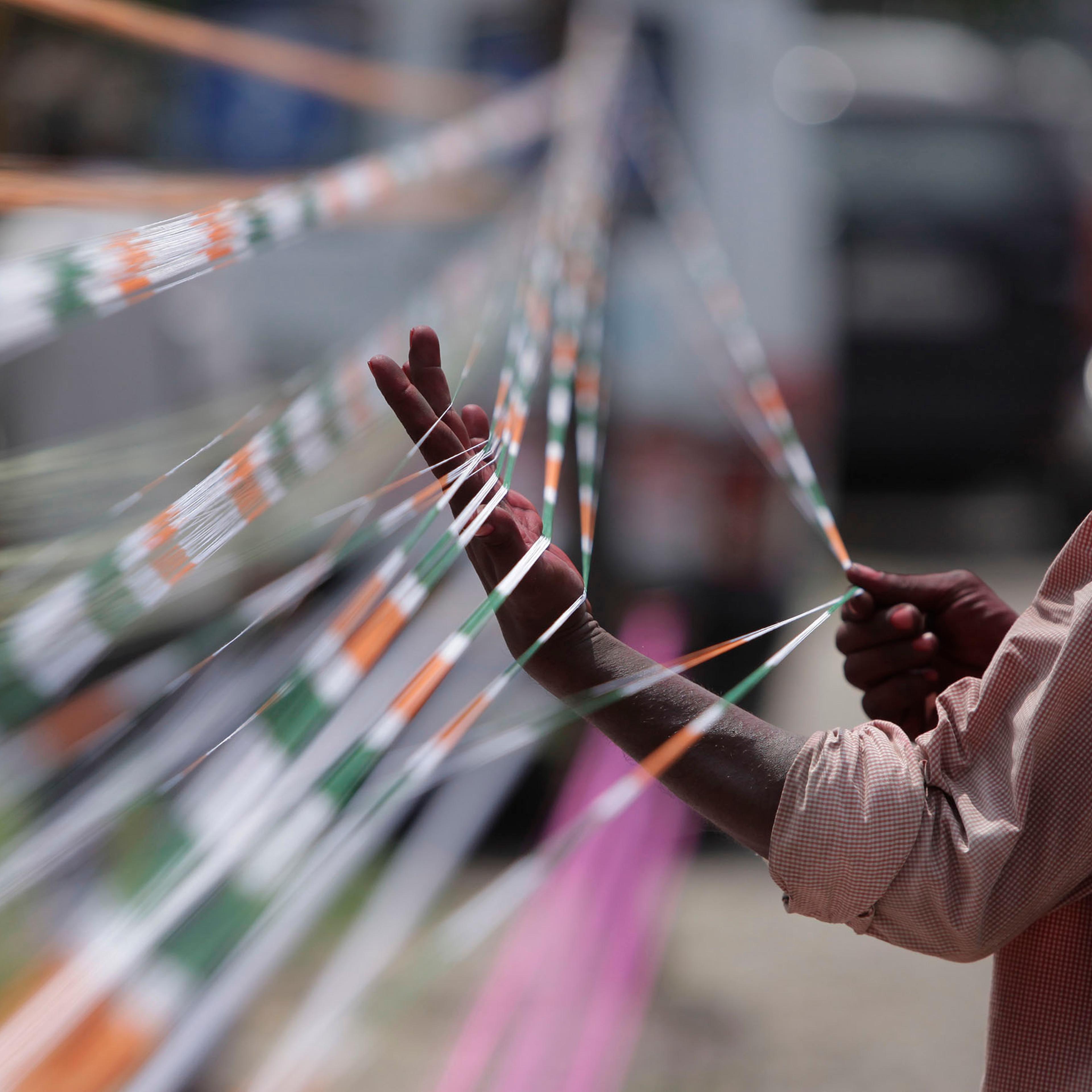 A professional thread maker prepares threads with the three colors of the Indian flag for flying kites in Jammu, India, Aug.13, 2016.
