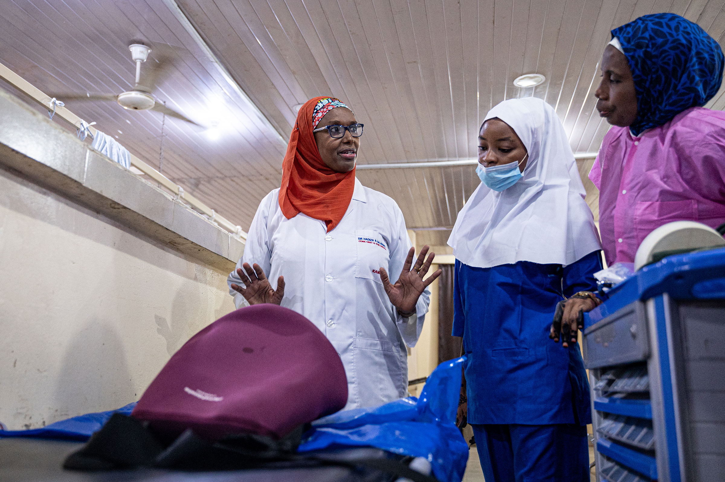Professor Hadiza Shehu Galadanci, Director of The African Center of Excellence for Population Health and Policy (ACEPHAP), demonstrates the use of the E-MOTIVE care bundle to Fatimah Sarikin Fulani (blue PPE) and Nafisa Abbas (pink) in the E-MOVITE resea