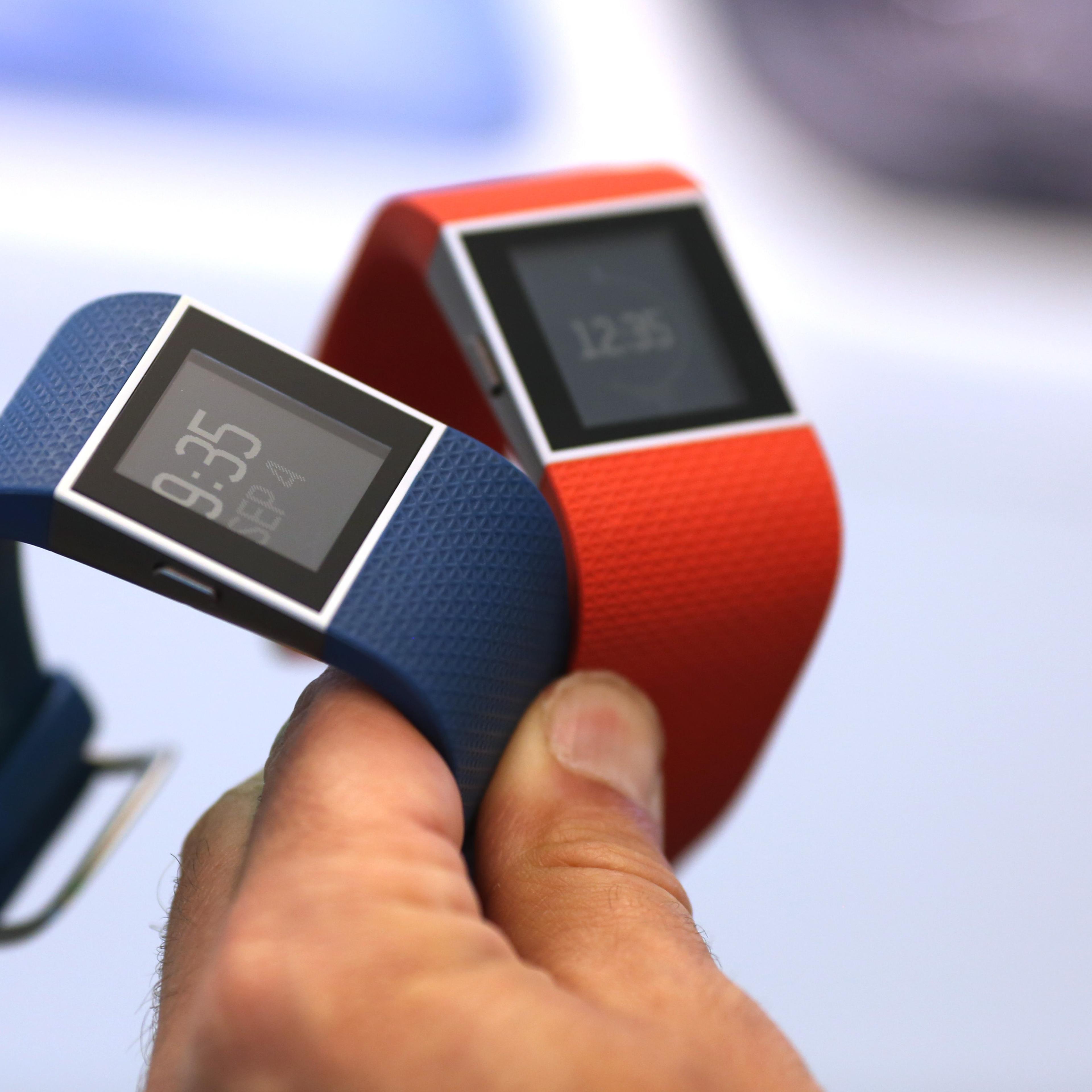 An employee holds Fitbit Inc. Surge smartwatches during the IFA International Consumer Electronics Show in Berlin, Germany, on Friday, Sept. 4, 2015.