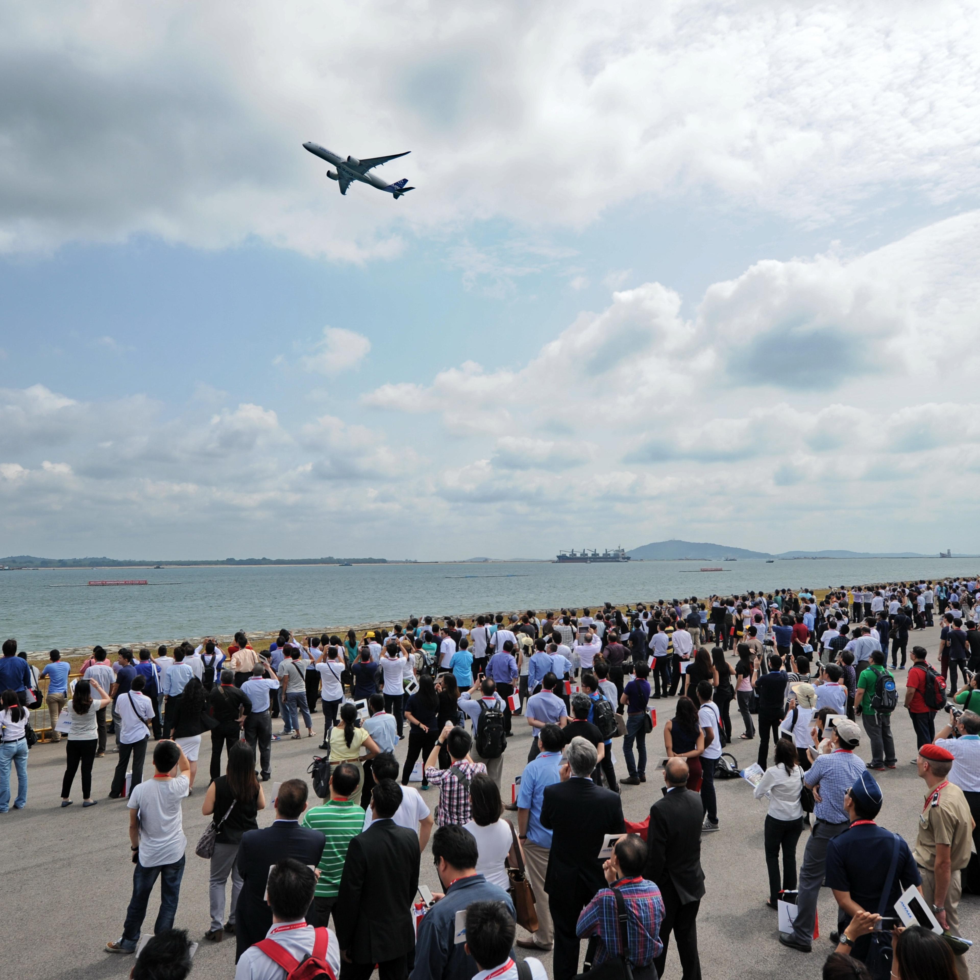 Visitors watch as a Airbus A350 flies past during the Singapore Airshow on Feb. 12, 2014.