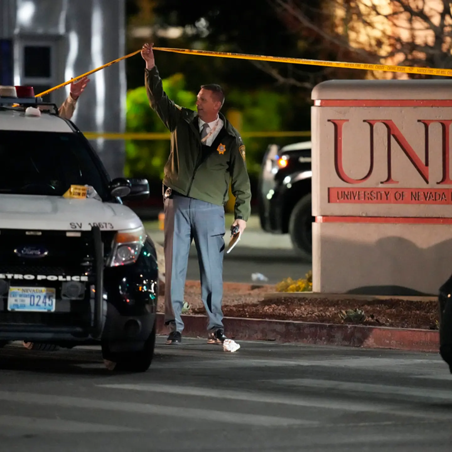 A police officer walks under crime scene tape in the aftermath of a shooting at the University of Nevada, Las Vegas, Wednesday, Dec. 6, 2023, in Las Vegas.