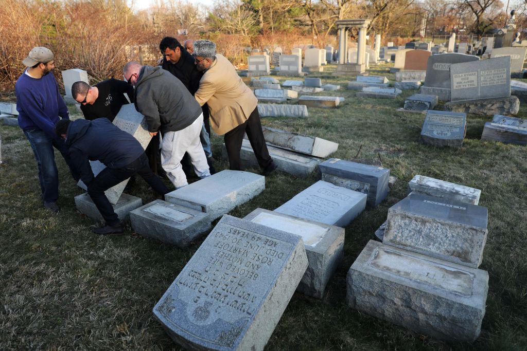 Volunteers help lift a fallen tombstone at the Jewish Mount Carmel Cemetery on Feb. 26, 2017 in Philadelphia, PA.