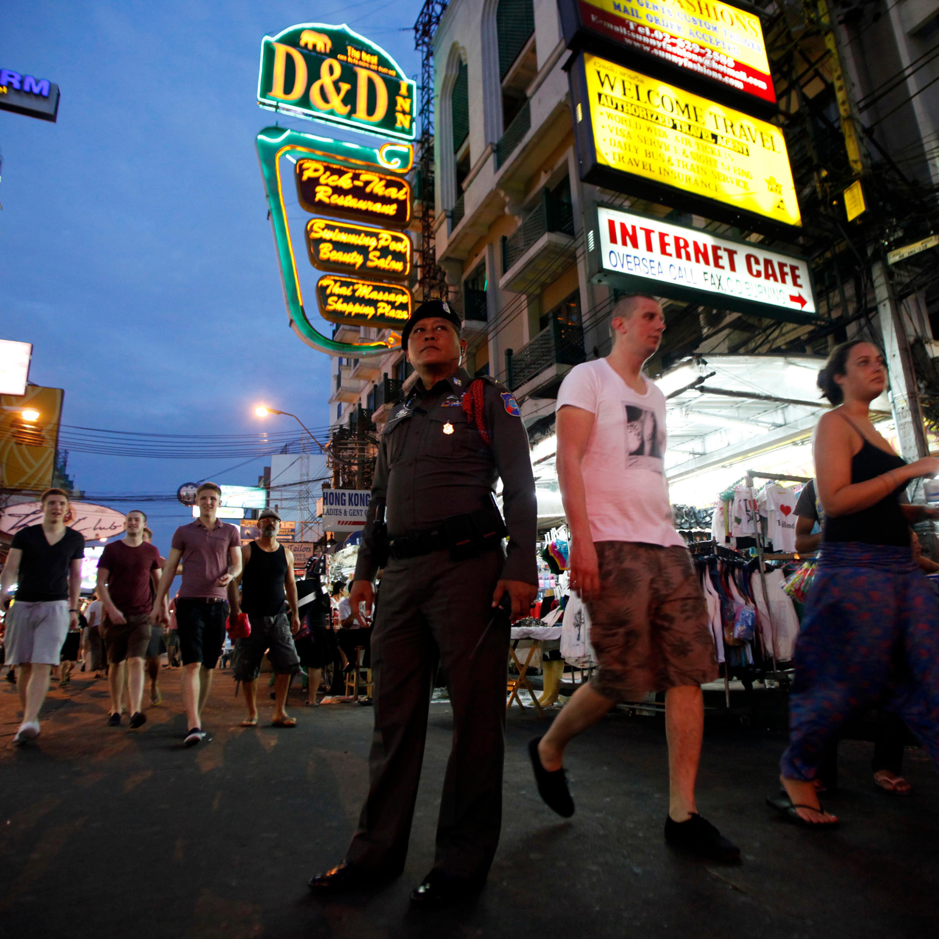 A tourist policeman stands guard as tourists walk along Khao San road in Bangkok