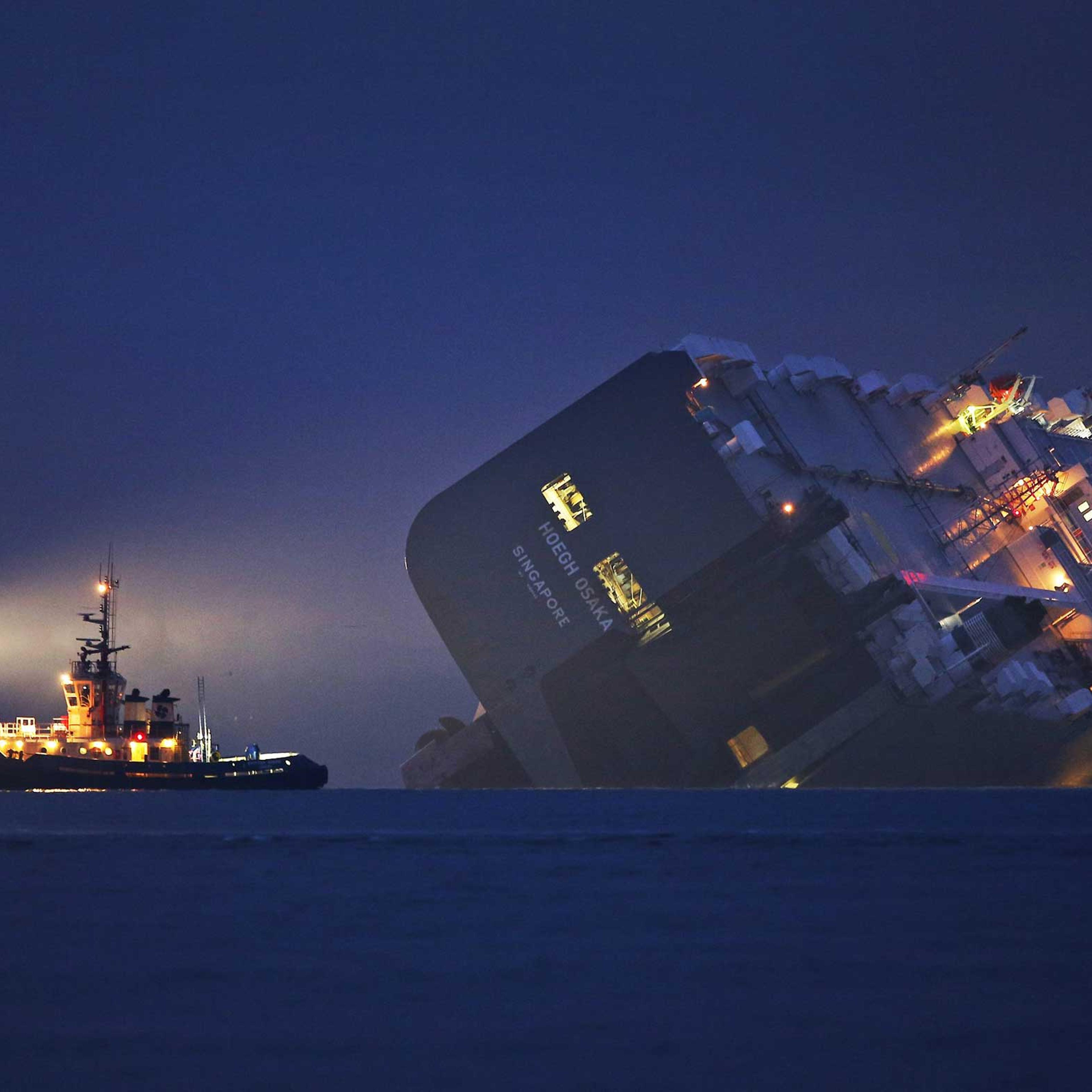 Jan 4. 2015. A salvage tug lights the hull of the stricken Hoegh Osaka cargo ship after it ran aground on a sand bank Cowes, England.