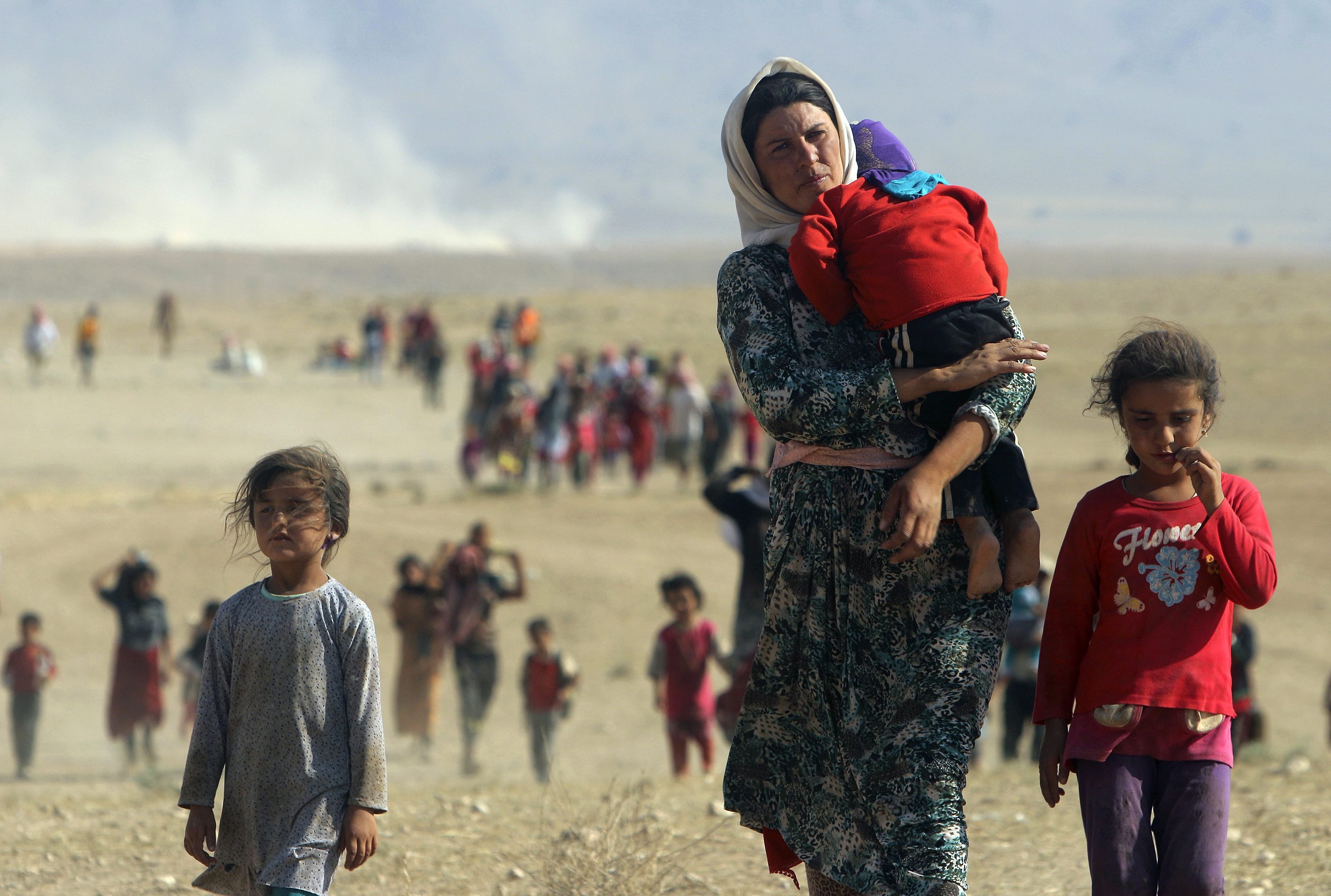 Displaced people from the minority Yazidi sect, fleeing violence from forces loyal to the Islamic State in Sinjar town, walk towards the Syrian border, on the outskirts of Sinjar mountain, near the Syrian border town of Elierbeh of Al-Hasakah Governorate