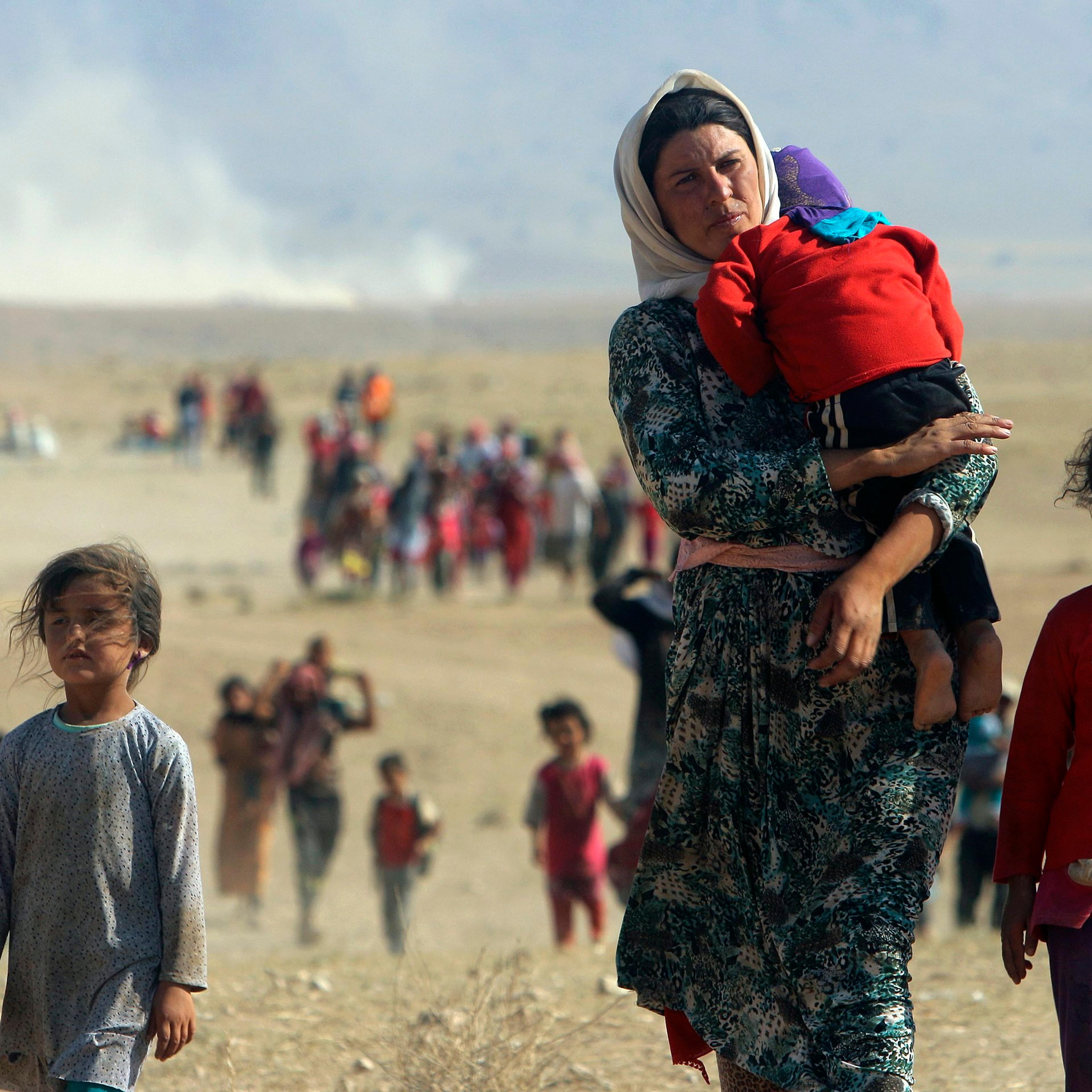 Displaced people from the minority Yazidi sect, fleeing violence from forces loyal to the Islamic State in Sinjar town, walk towards the Syrian border, on the outskirts of Sinjar mountain, near the Syrian border town of Elierbeh of Al-Hasakah Governorate