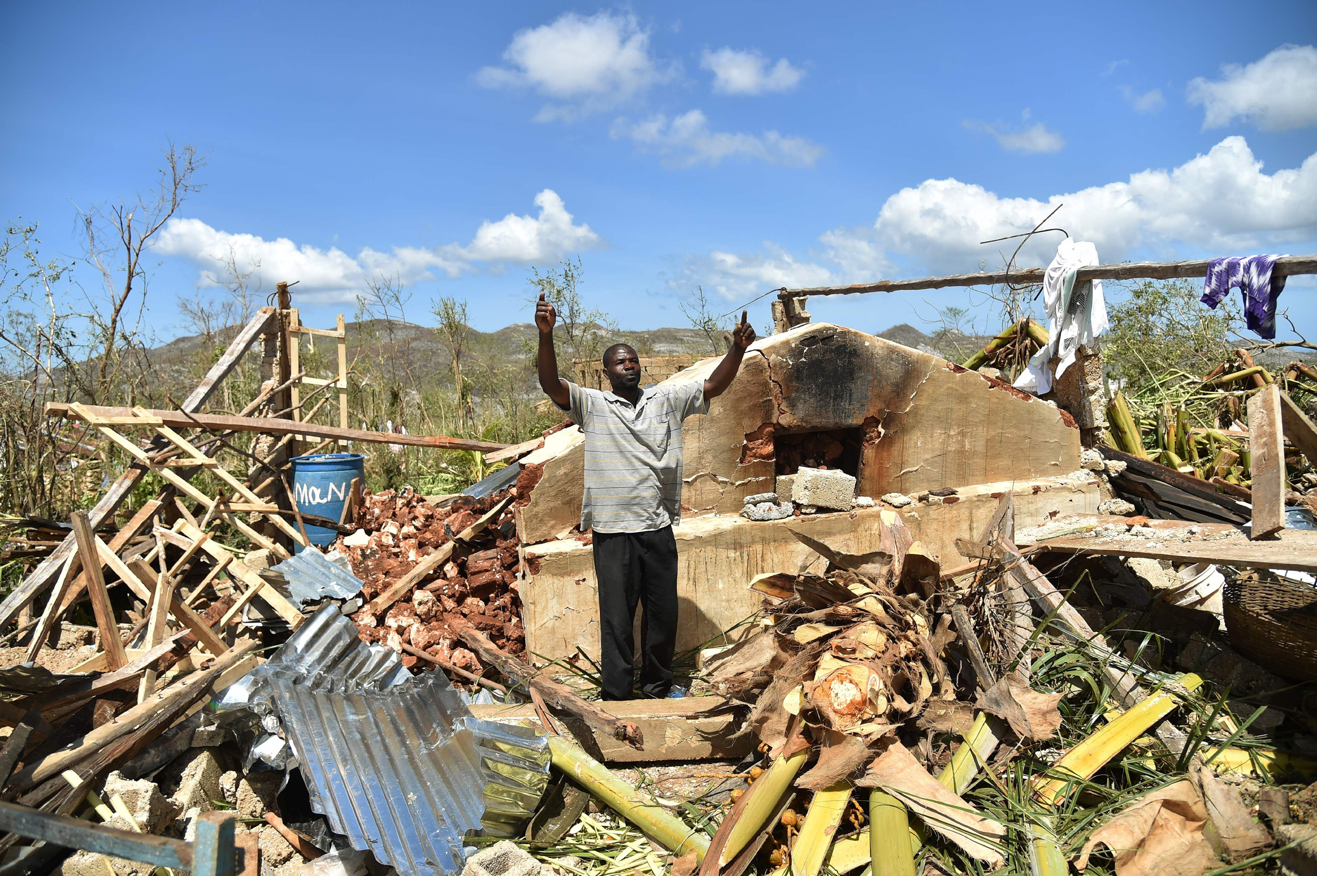 A man gestures while stangin in his house that was damaged in hurricane Matthew, in Deson, near Les Cayes in southwest Haiti, on October 7, 2016. The full scale of the devastation in hurricane-hit rural Haiti became clear as the death toll surged over 40