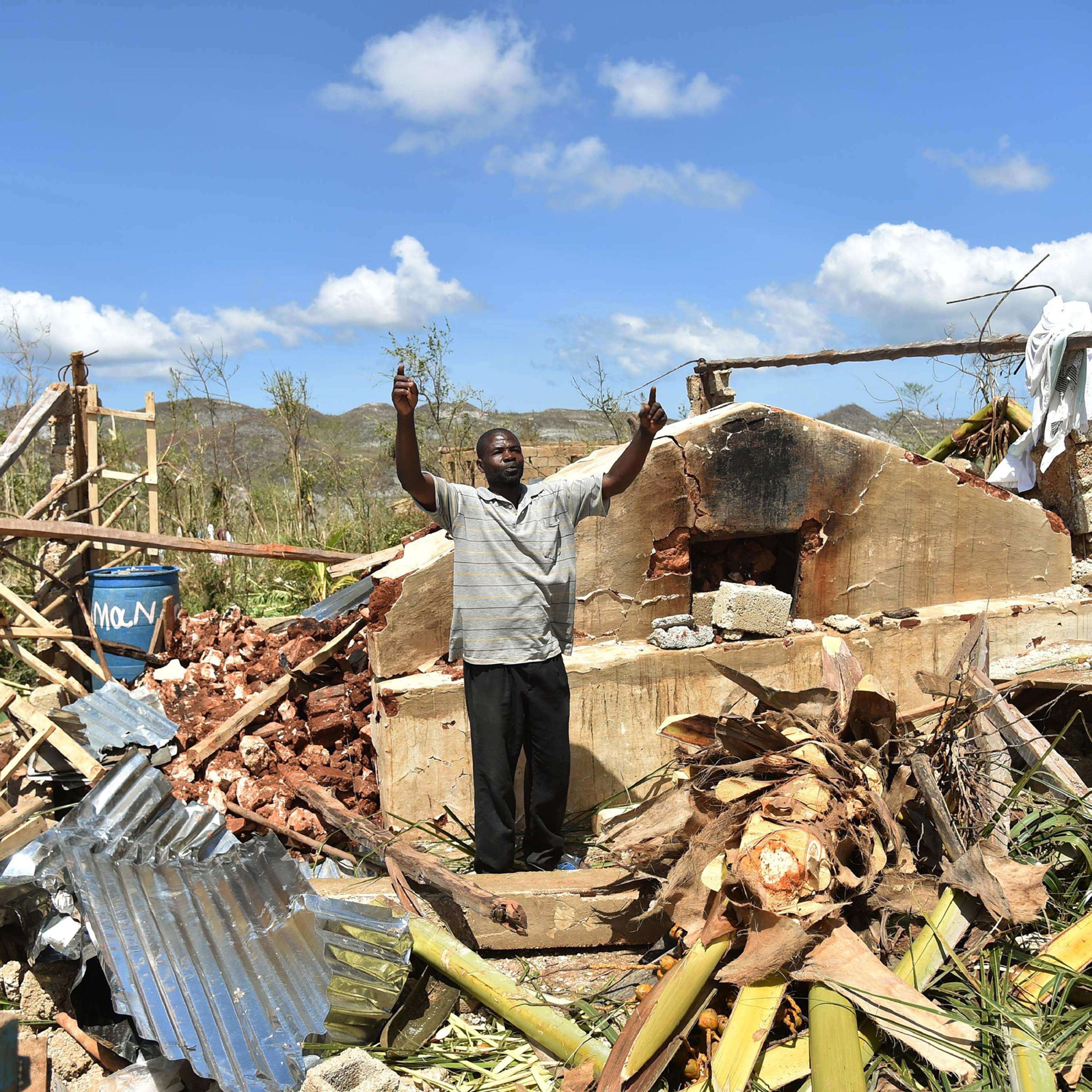 A man gestures while stangin in his house that was damaged in hurricane Matthew, in Deson, near Les Cayes in southwest Haiti, on October 7, 2016. The full scale of the devastation in hurricane-hit rural Haiti became clear as the death toll surged over 40