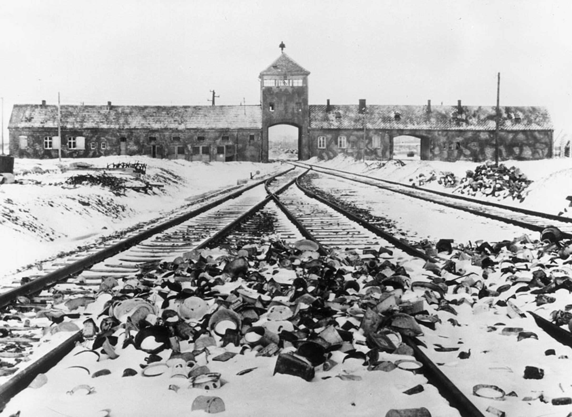 Snow-covered personal effects of those deported to the Auschwitz concentration camp in Poland litter the train tracks leading to the camp's entrance, circa 1945.