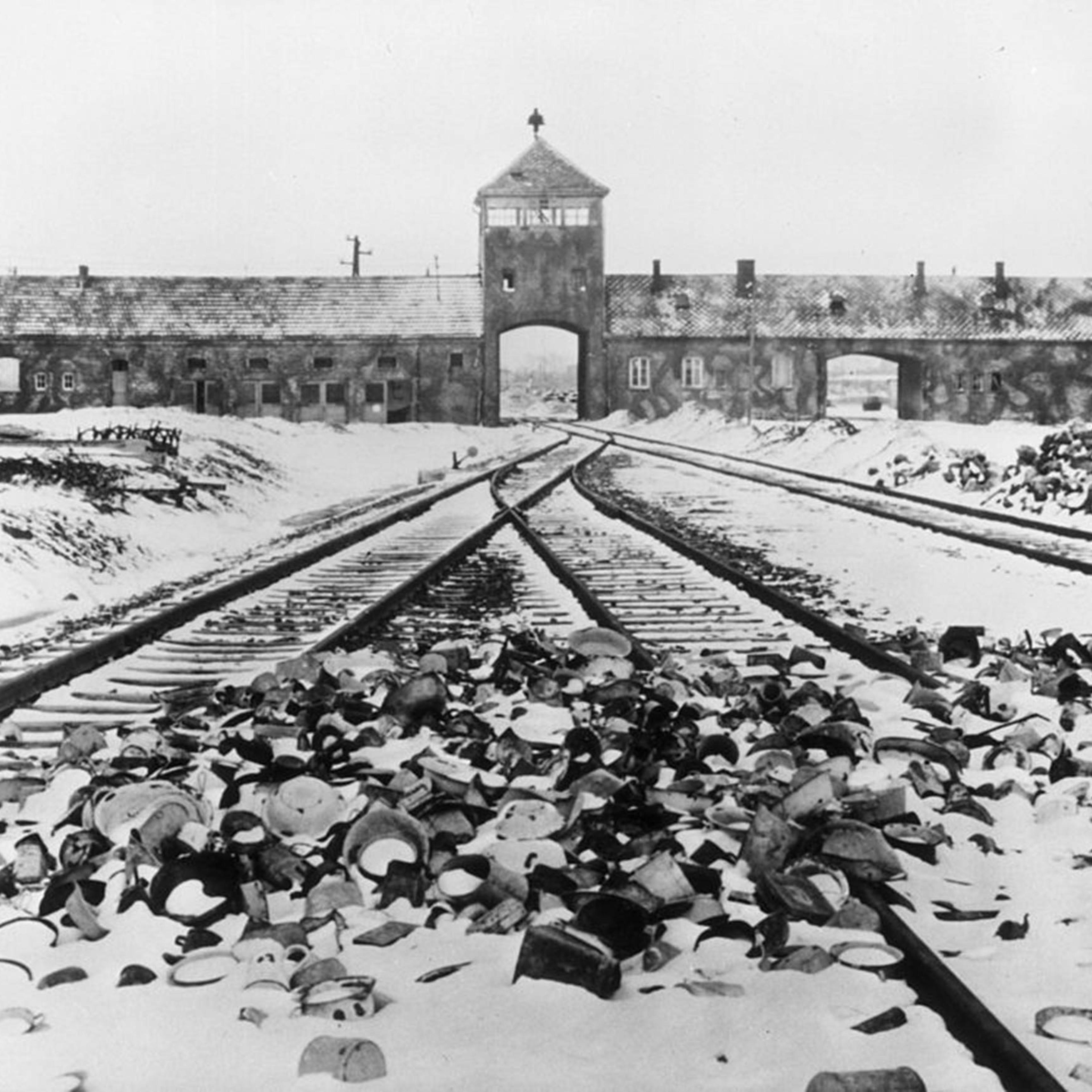 Snow-covered personal effects of those deported to the Auschwitz concentration camp in Poland litter the train tracks leading to the camp's entrance, circa 1945.