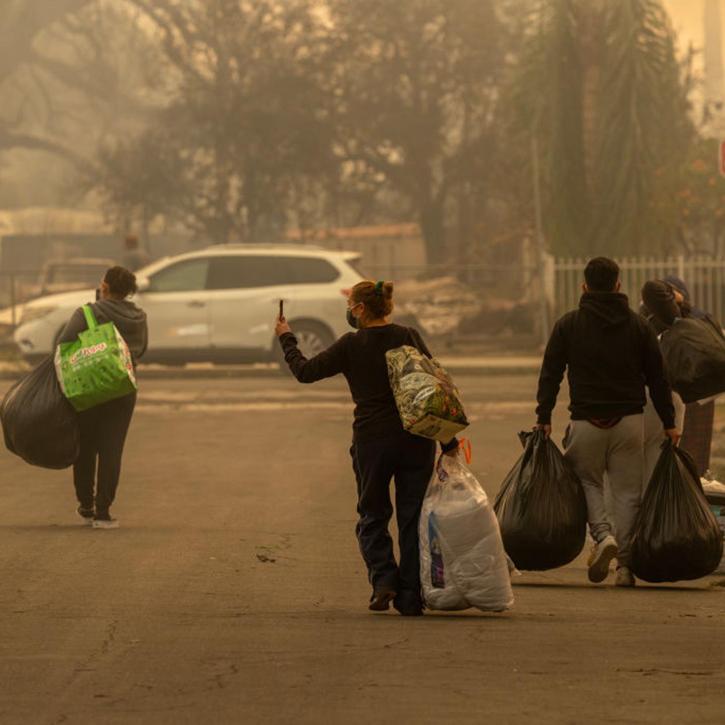 People carry possessions through a neighborhood where a large part of the homes burned in the Eaton Fire in Altadena, Calif. on Jan. 8, 2025.