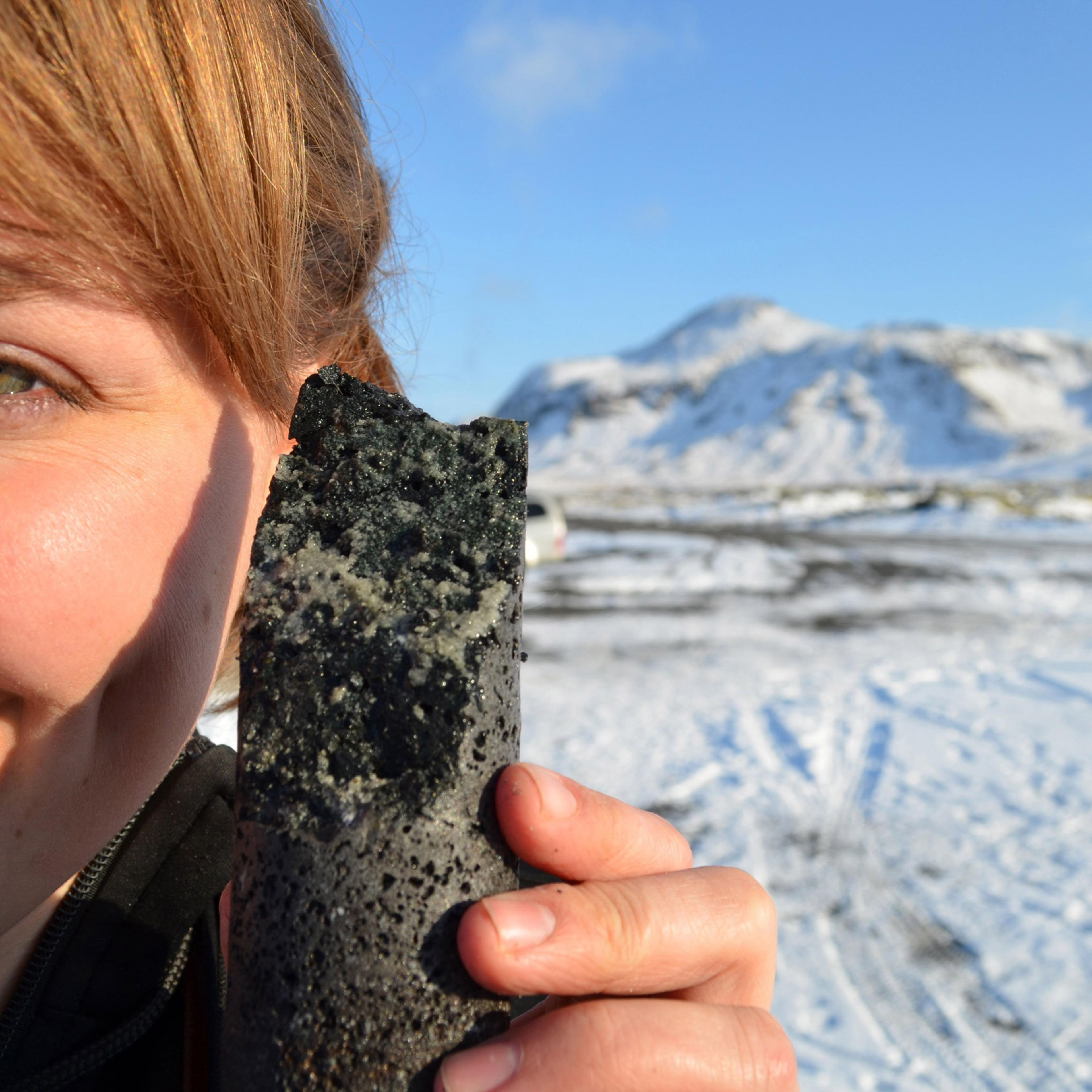 An experimental drill core held by coauthor Sandra Snaebjornsdottir in Iceland, laced with solidified carbonate, apparently produced by a new process that turns carbon emissions to stone when pumped underground.