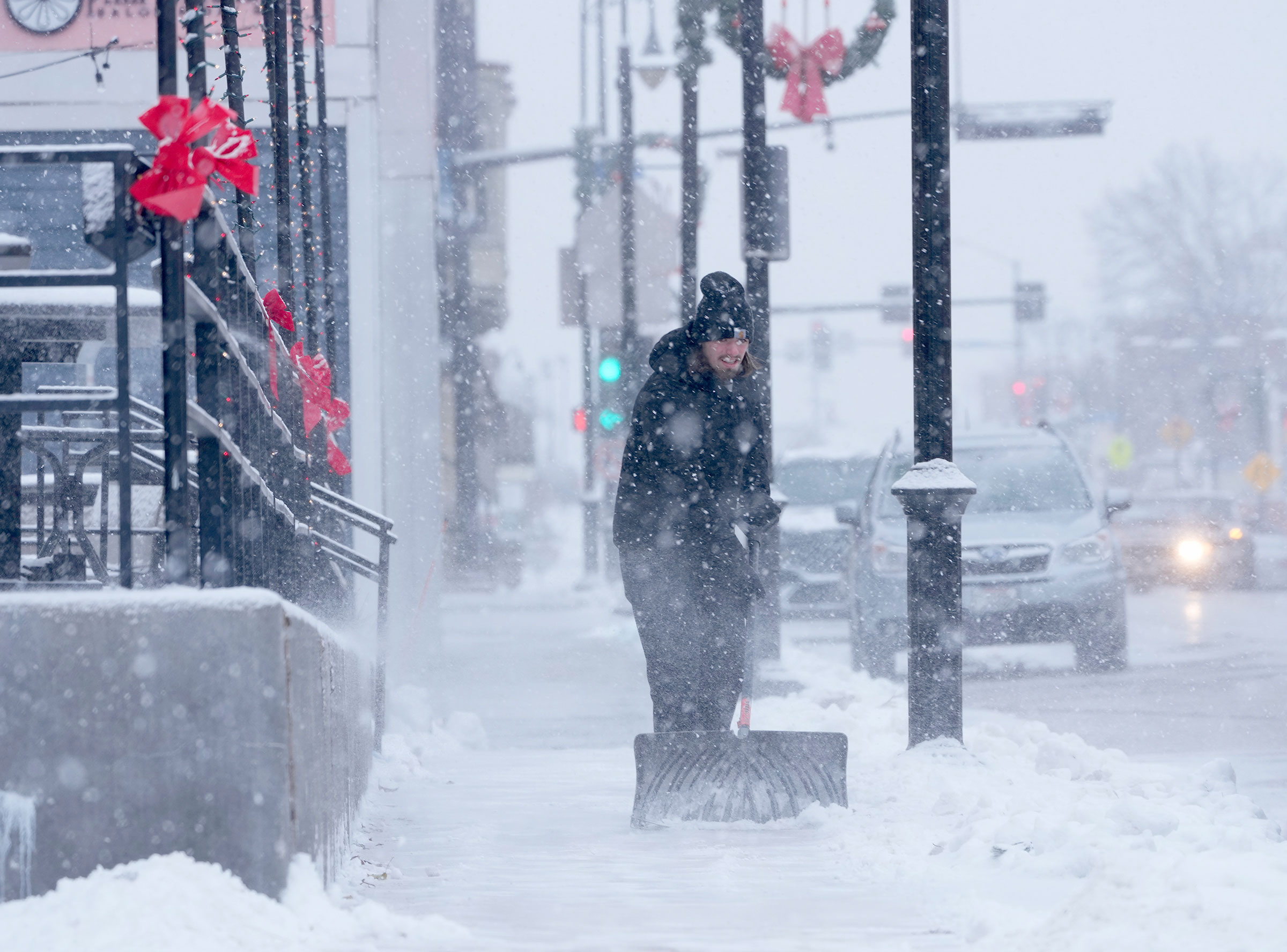 Carson Batchelor, a server at the Hot House Tavern, shovels snow from the sidewalk in front of the business in Menomonee Falls, Wis., on Dec. 22, 2022.