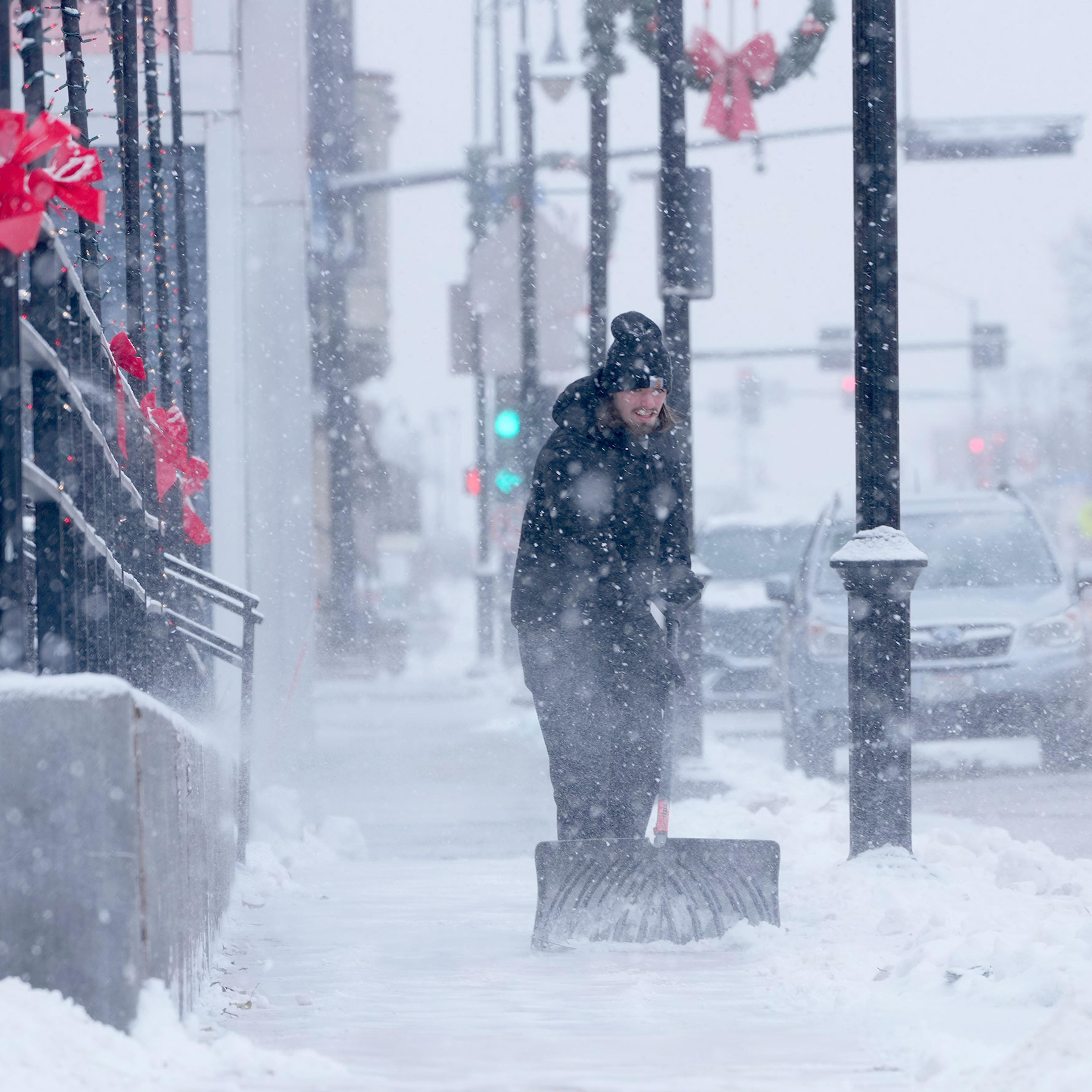 Carson Batchelor, a server at the Hot House Tavern, shovels snow from the sidewalk in front of the business in Menomonee Falls, Wis., on Dec. 22, 2022.