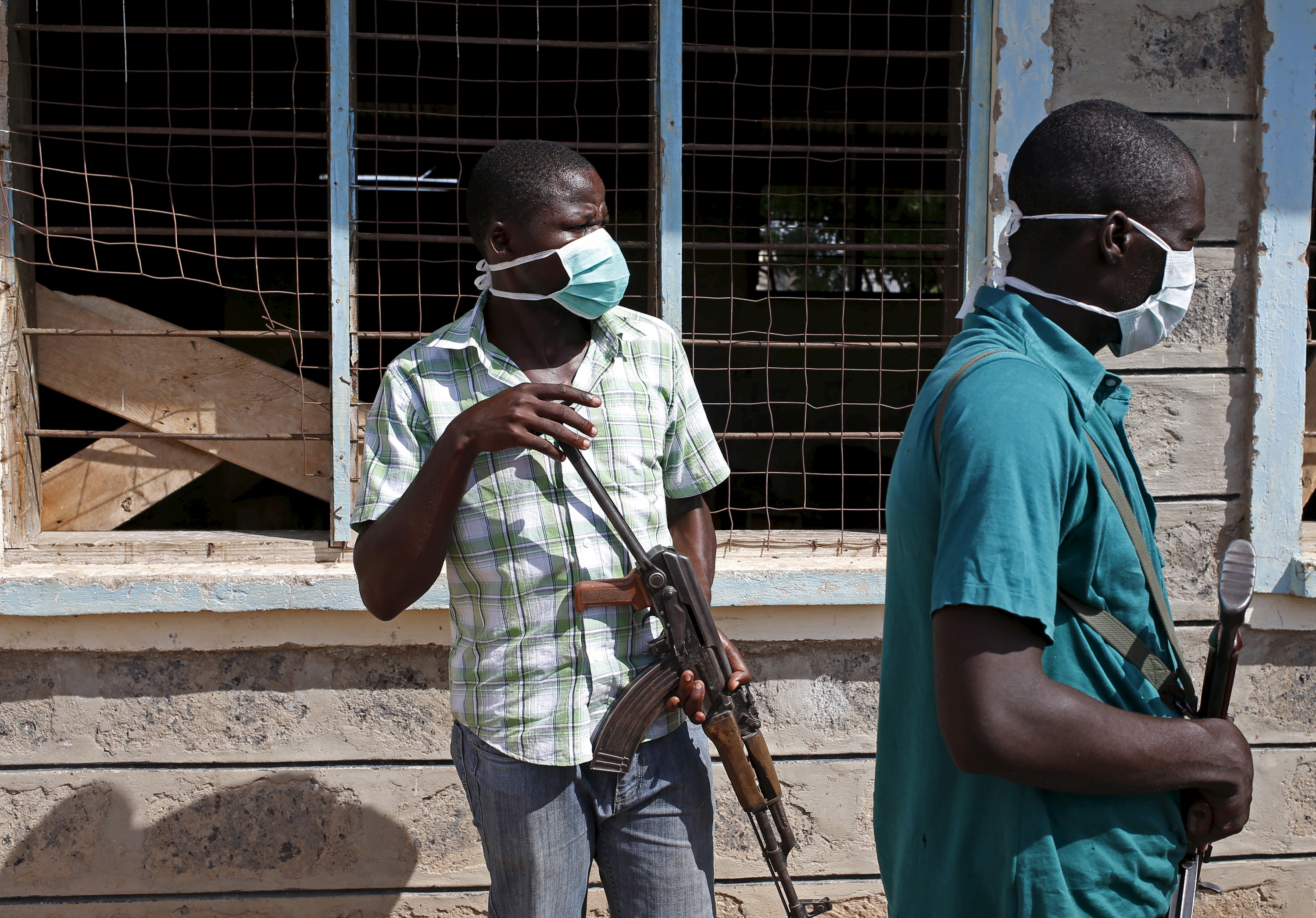 Plainclothes policemen stand in front of a crowd which came to see bodies of suspected Garissa University College attackers in a school compound in Garissa