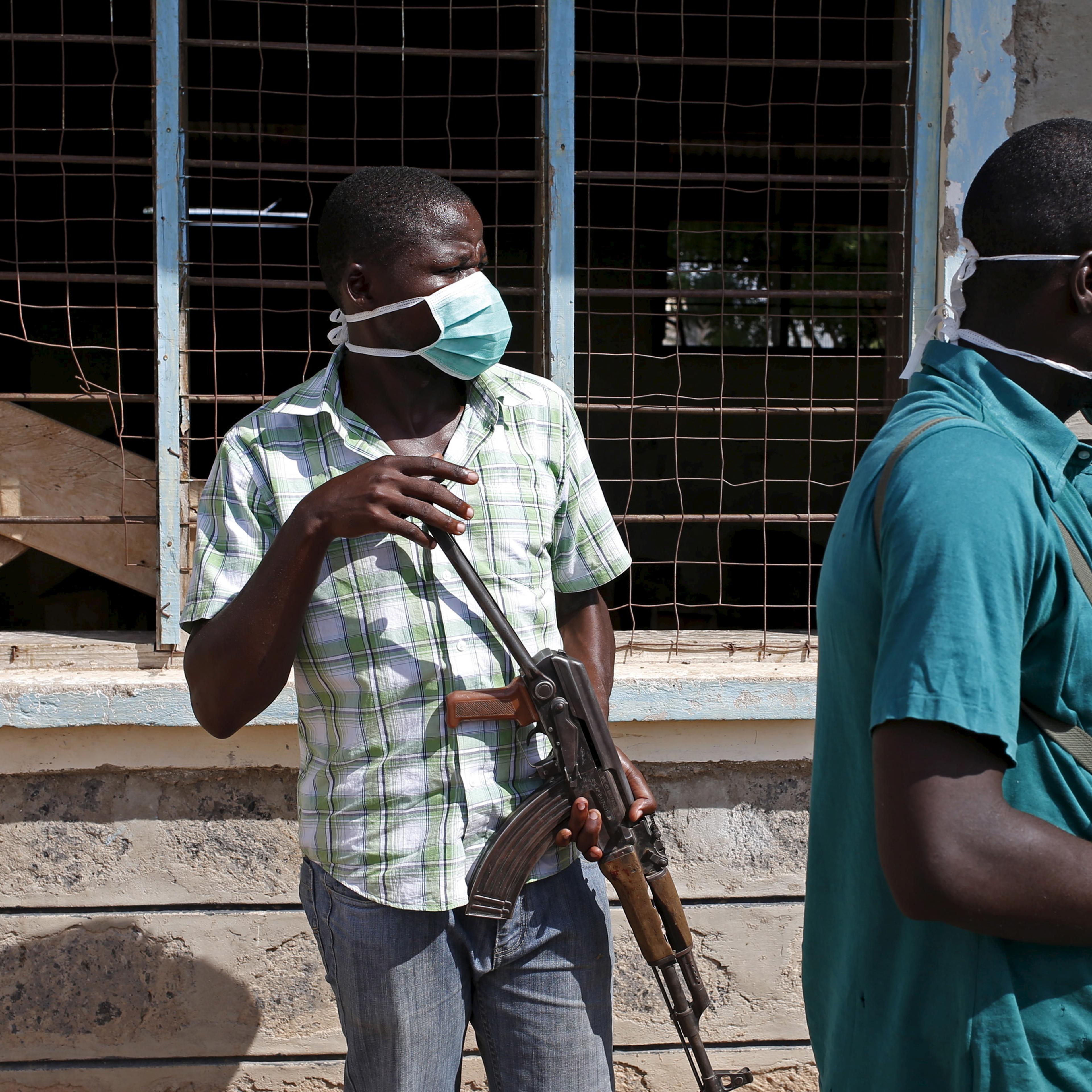 Plainclothes policemen stand in front of a crowd which came to see bodies of suspected Garissa University College attackers in a school compound in Garissa
