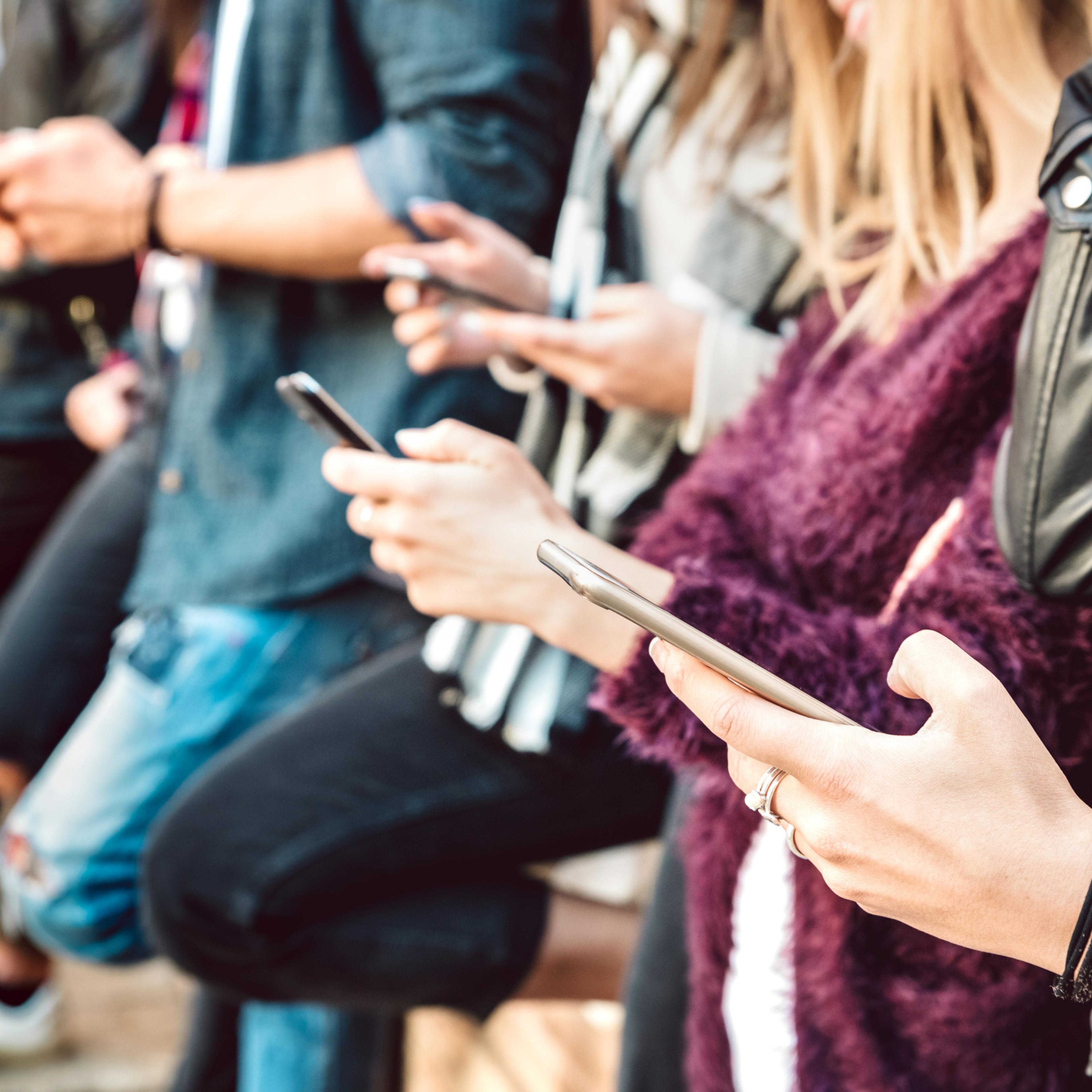 View of friends hands sharing content on mobile cell phones.