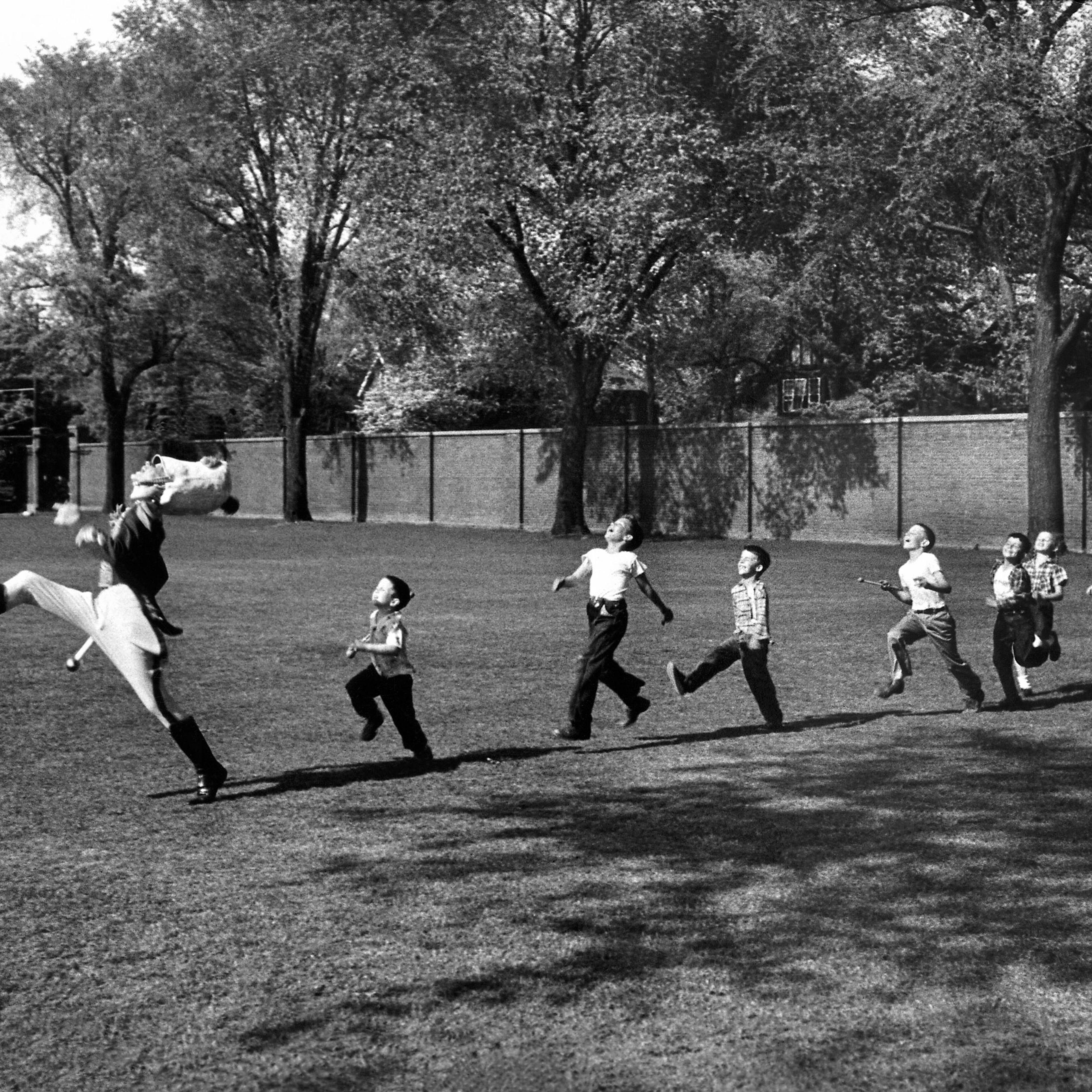 The drum major for the University of Michigan marching band high-steps as children follow suit, 1950.